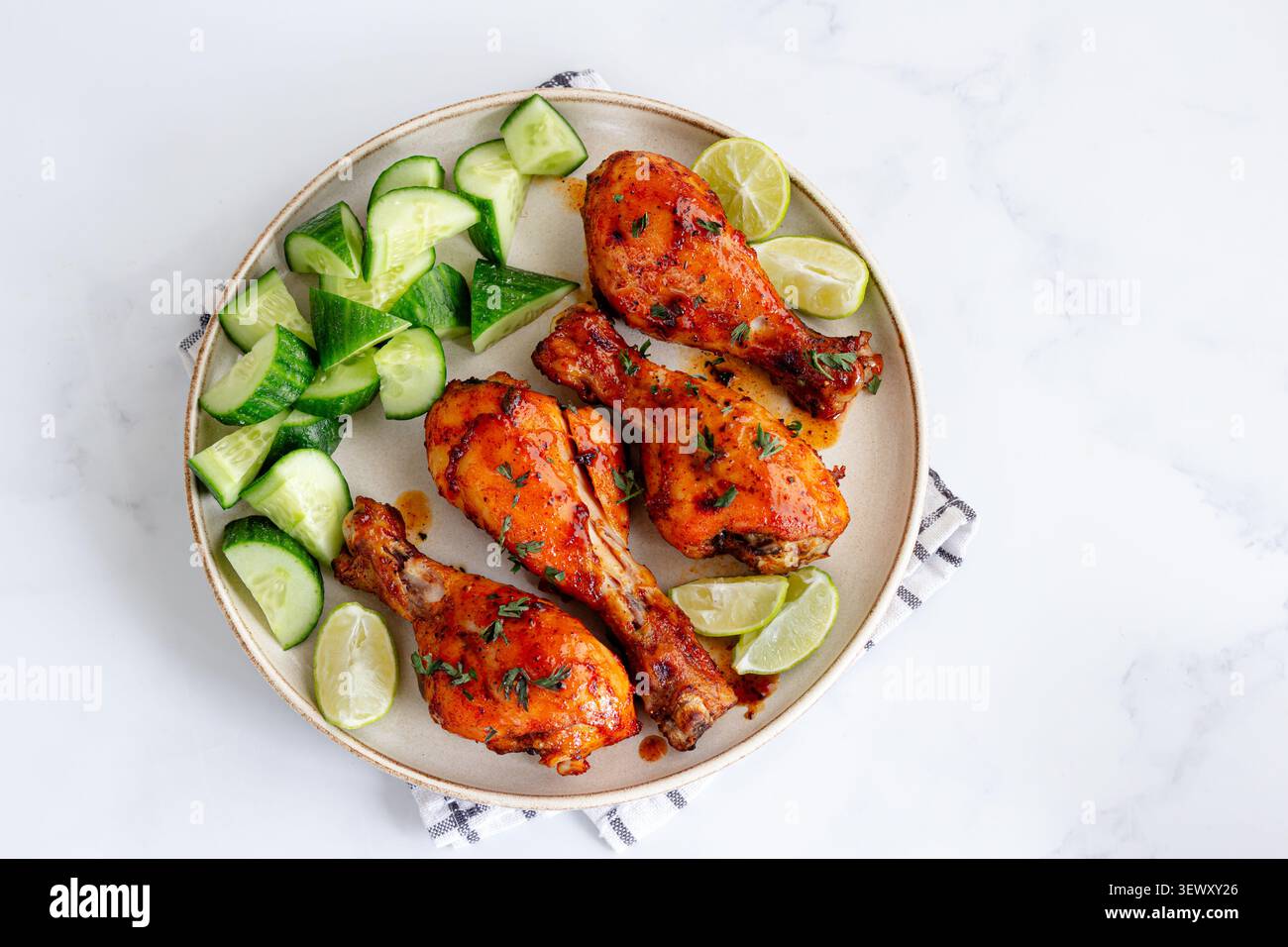 Pilons de poulet épicés servis avec une salade de concombre Banque D'Images