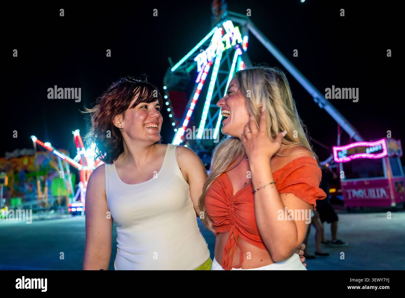 Amis riant profitant d'une nuit d'été au parc d'attractions Banque D'Images