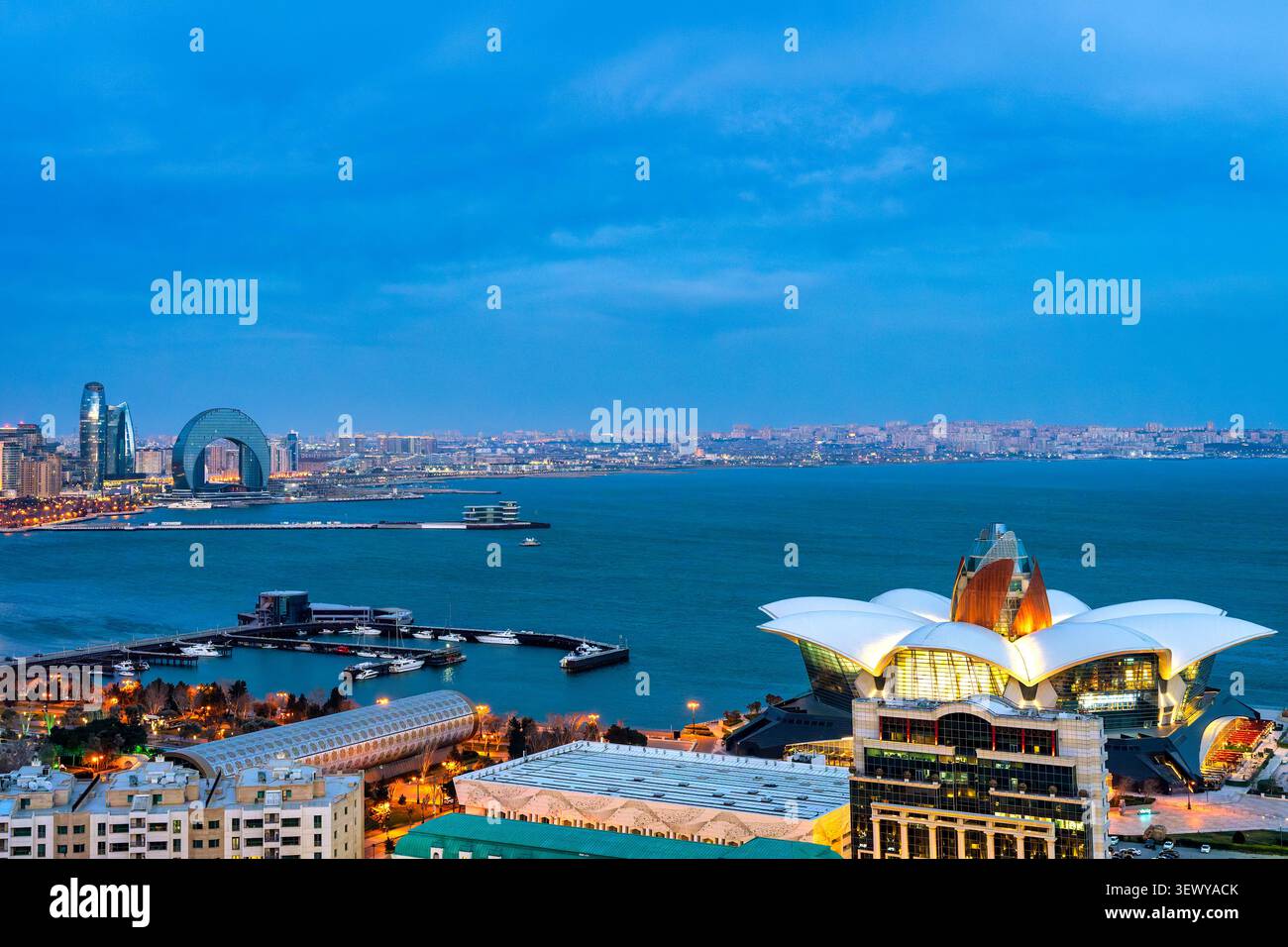 Vue aérienne à l'heure bleue du toit en forme de lotus du centre commercial Deniz avec la baie de Bakou, l'hôtel Crescent et les tours de Port Baku au-delà, Bakou, Azerbaïdjan. Banque D'Images