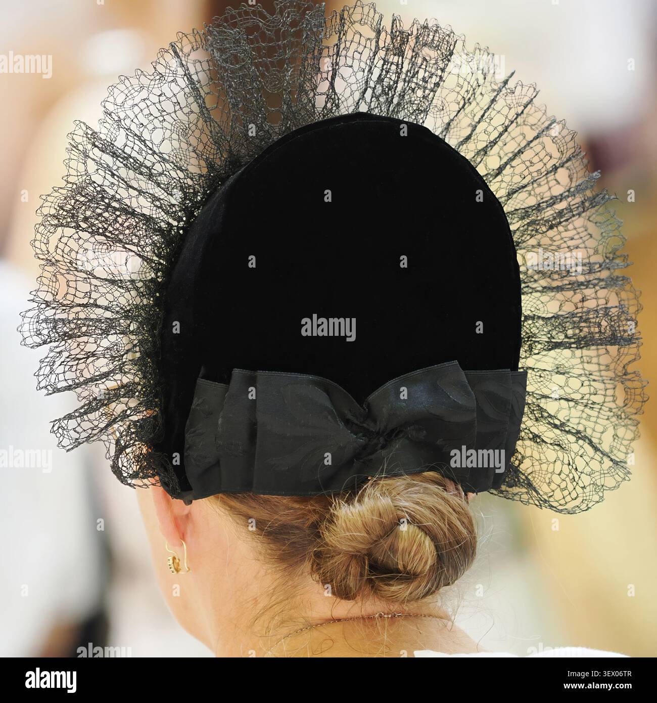 Vue arrière d'une femme portant une coiffe traditionnelle en dentelle noire et un bonnet avec un chignon Banque D'Images