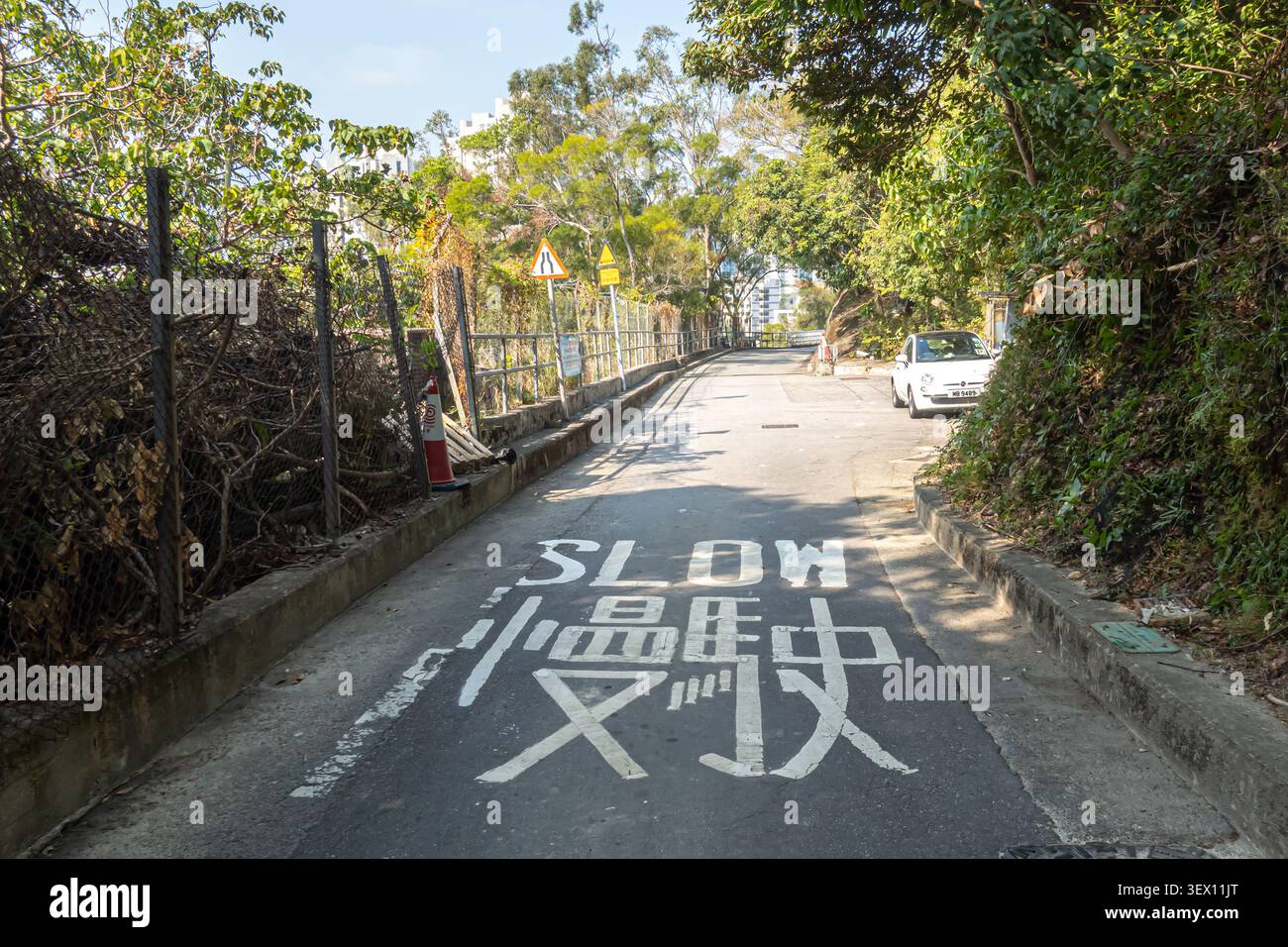 Le panneau sur la route indique « Slow » en anglais et en chinois, marquage routier bilingue sur Brick Hill, standard à Hong Kong Banque D'Images