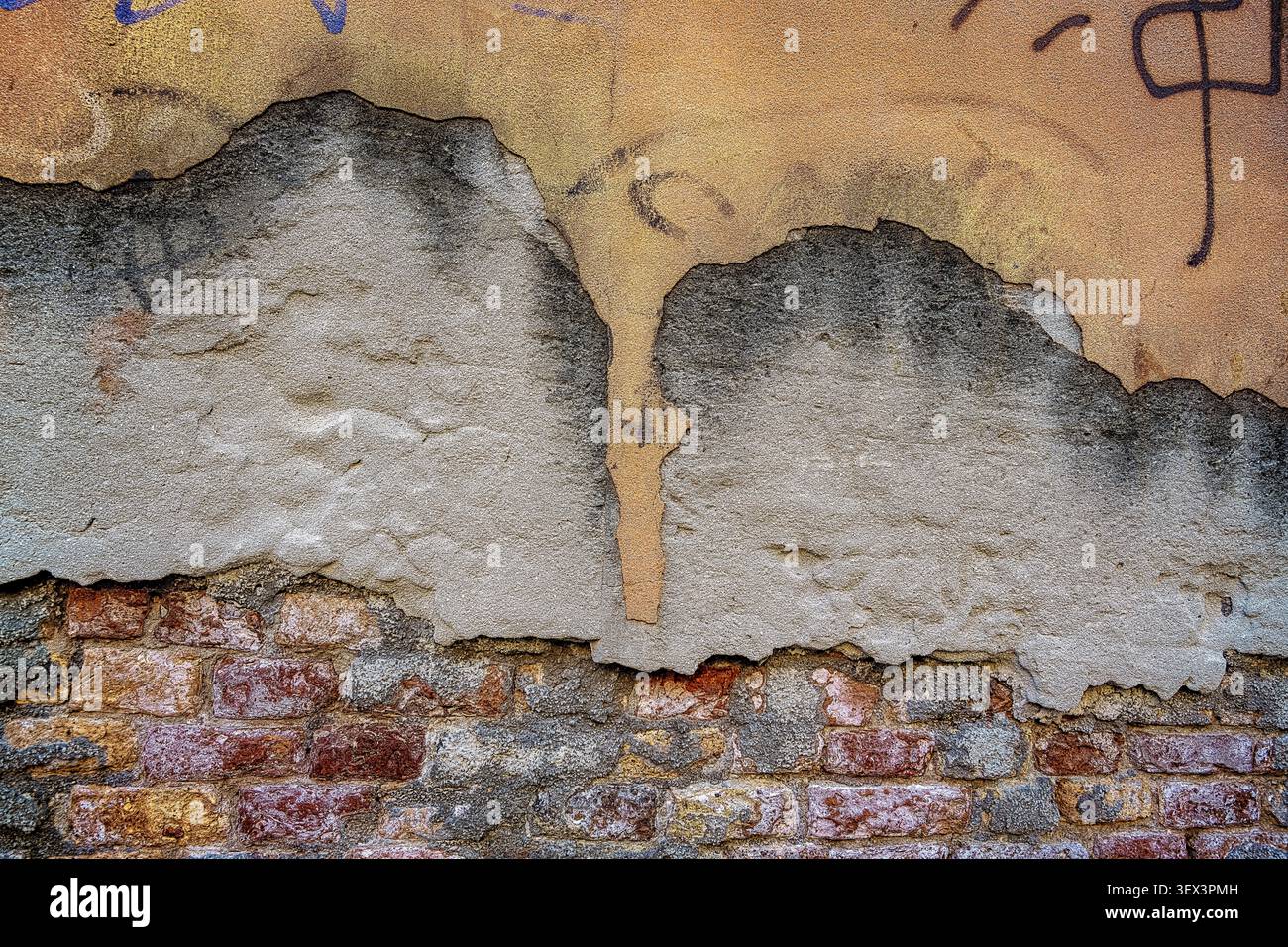 Plâtre tombant d'un vieux mur de briques. Vieux mur fissuré et ruiné en briques rouges avec des restes de plâtre à Venise, Italie Banque D'Images