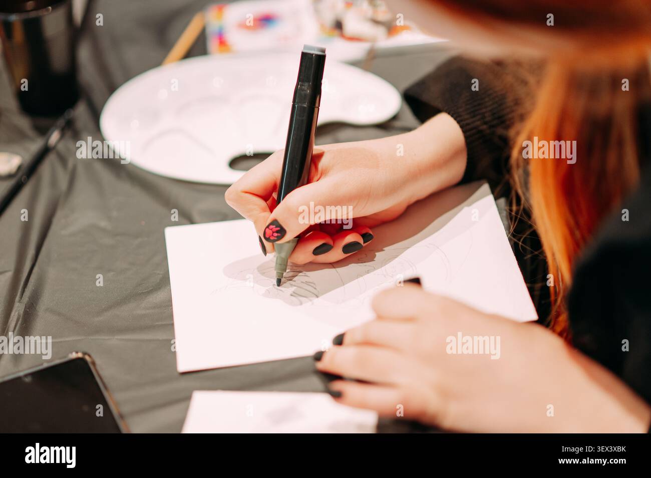 Femme esquissant un design de mode avec marqueur pendant un atelier créatif Banque D'Images