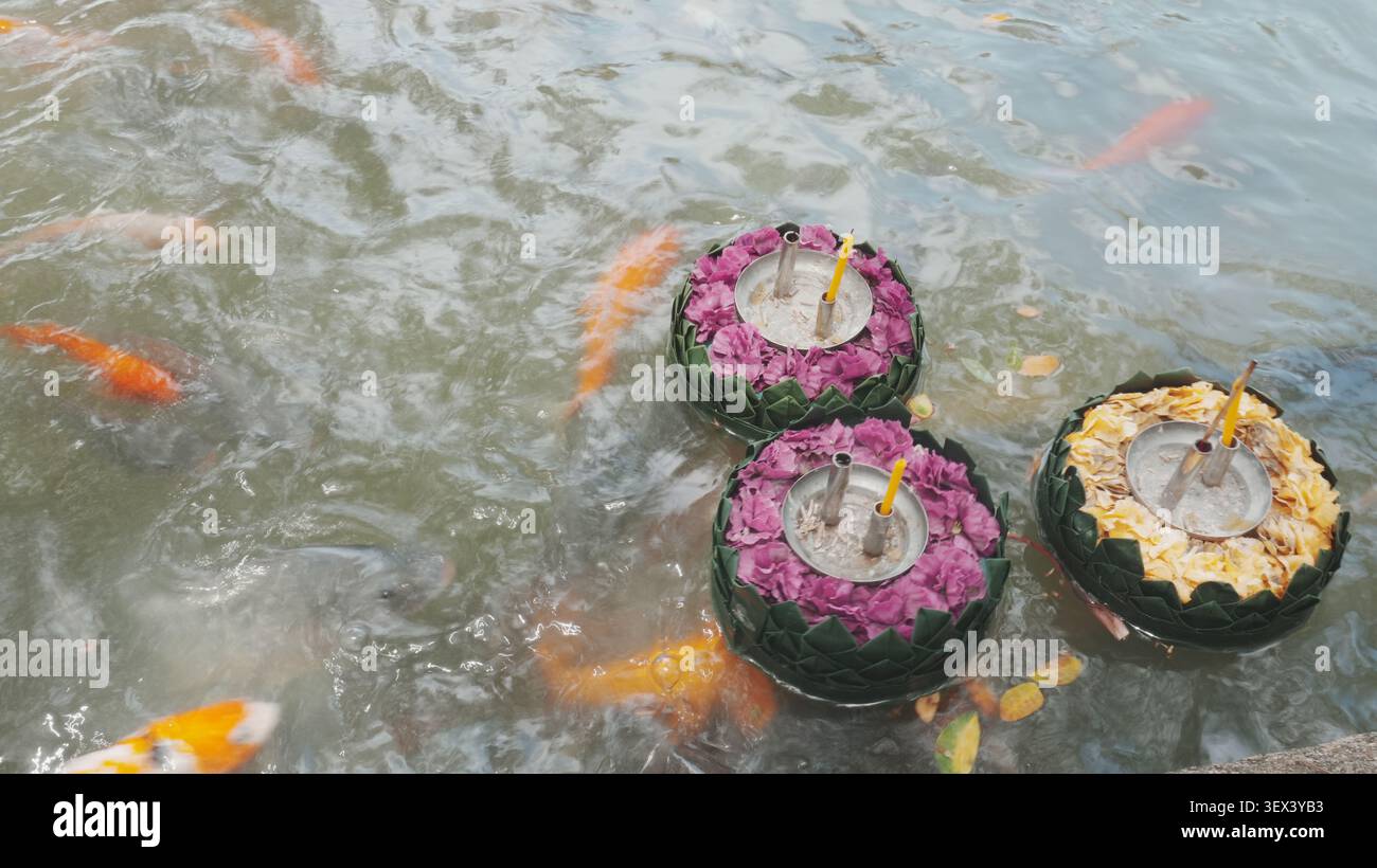 Vue de dessus trois krathong fleuris ornés flottant sur la surface de l'eau tranquille de Garden Pond Banque D'Images