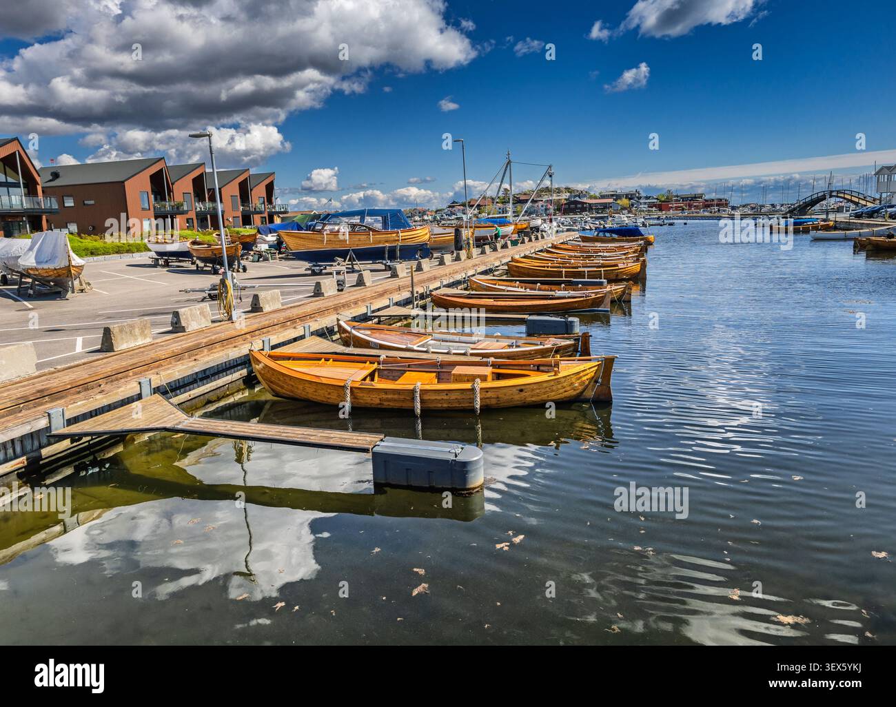 Vue aérienne de petits bateaux en bois amarrés dans un port paisible sous un ciel bleu vif avec des nuages dispersés. Banque D'Images