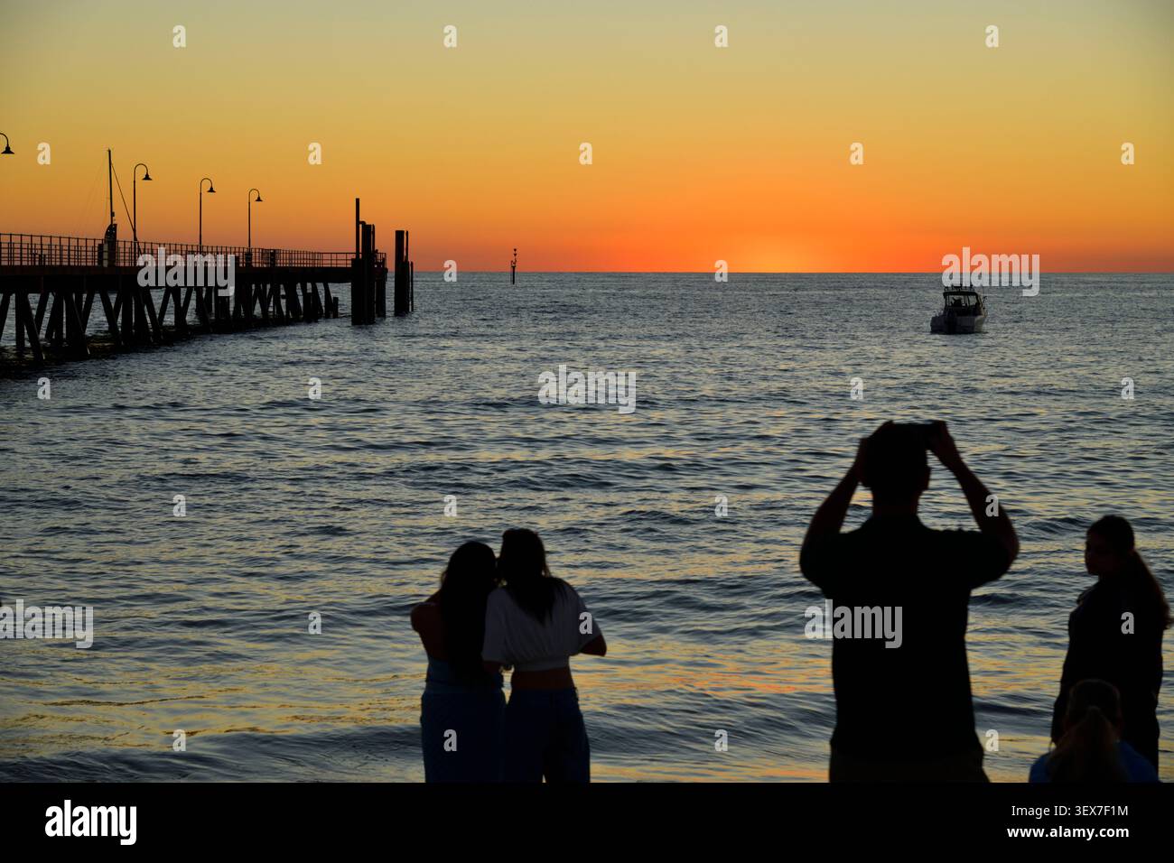 Australie, Australie méridionale, Adélaïde, quartier de Glenelg, silhouettes de touristes photographiant le coucher de soleil sur le golfe St Vincent, près de la jetée de Glenelg Banque D'Images