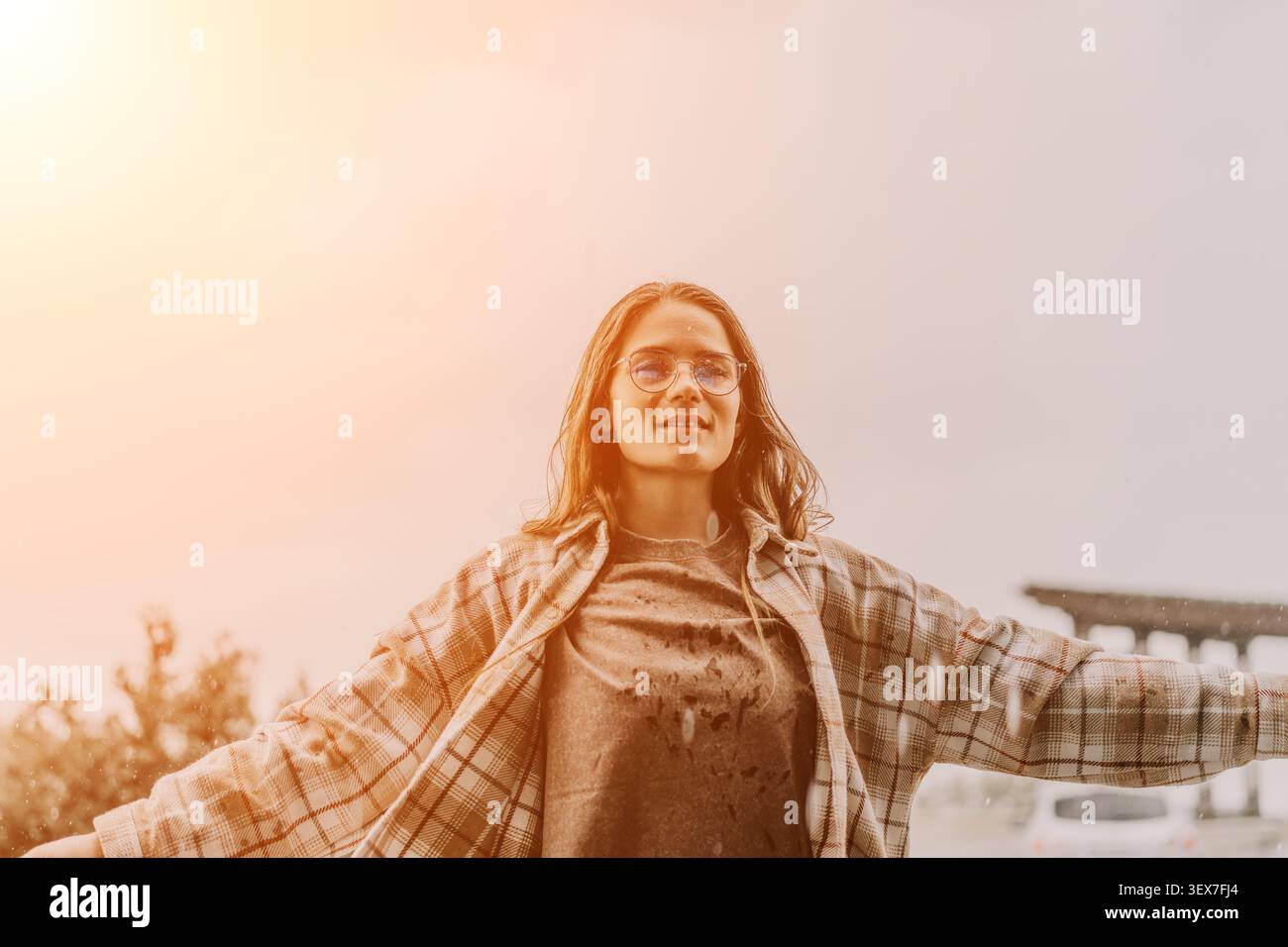 Femme liberté pluie se tient avec les bras grand ouvert sentiment libéré pendant une averse de coucher du soleil avec espace de copie Banque D'Images