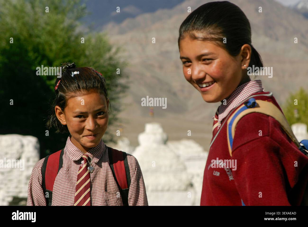 Les enfants en route pour l'école la vallée de l'Indus avec la chaîne Stok derrière eux à côté du monastère Thiksey près de Leh, Ladakh, Inde, août 2004 Banque D'Images
