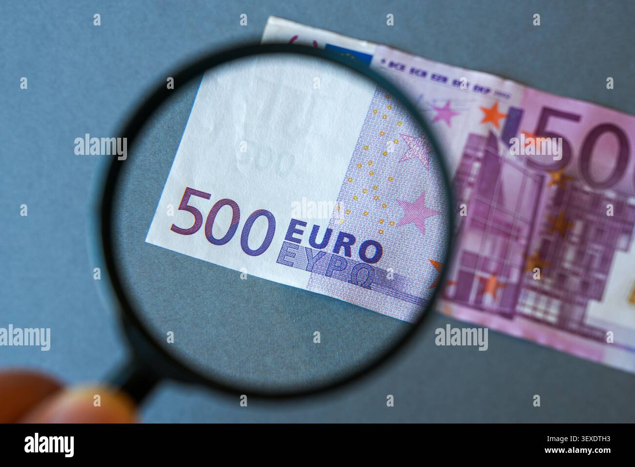Loupe inspectant un billet de 500 euros symbolisant la vérification de l'argent et la détection des contrefaçons Banque D'Images