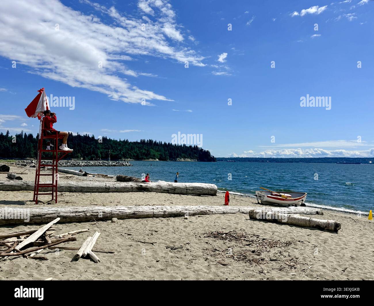 Sauveteur en service sur une plage de sable à West Vancouver, Colombie-Britannique, Canada, avec des bûches de bois flotté, une petite barque et des vues sur Burrard Inlet on Banque D'Images
