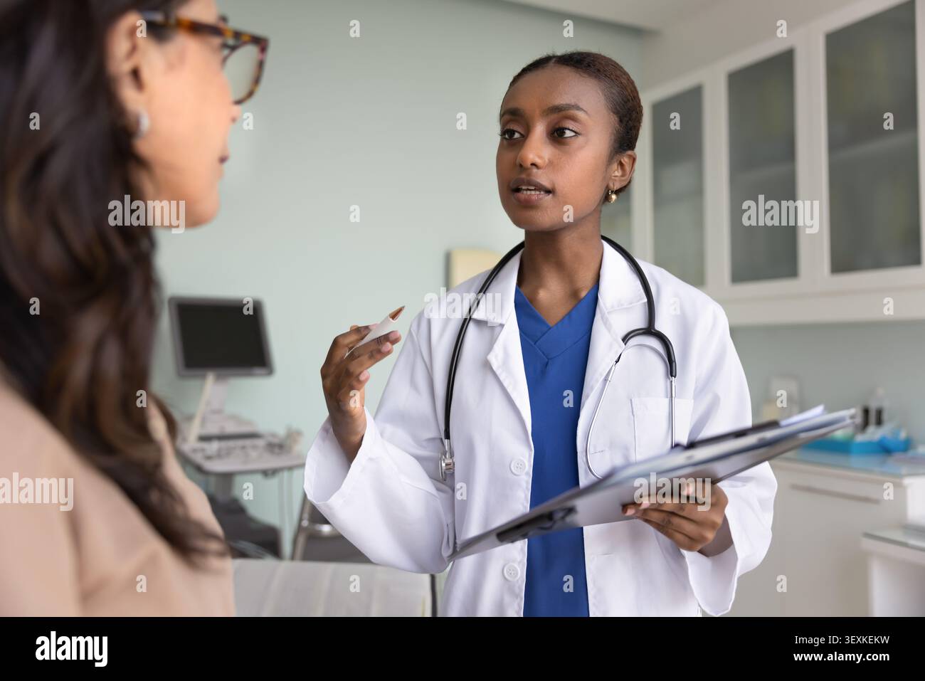 Jeune médecin afro-américain confiant donnant consultation à une femme mature Banque D'Images