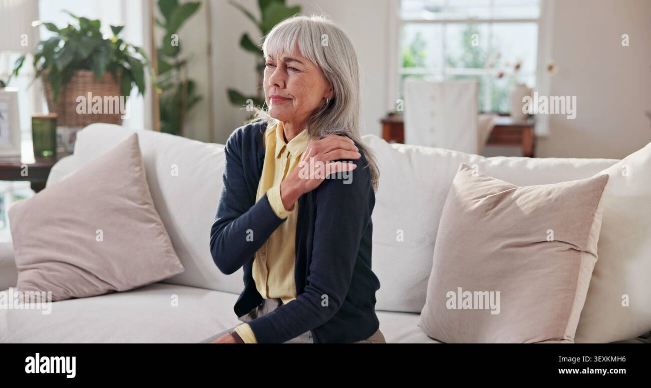 Senior, femme et inconfort avec douleur à l'épaule sur le canapé pour la fibromyalgie, l'arthrite et la tension. Retraite, retraité et tension musculaire dans la maison pour Banque D'Images