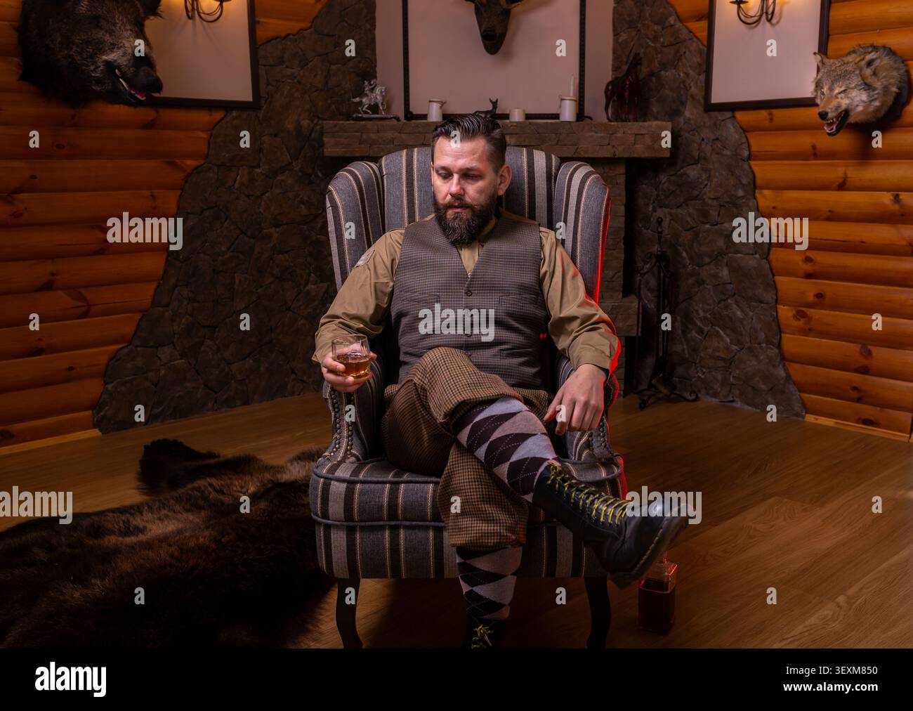 Un élégant gentleman se reposant dans un fauteuil confortable avec un verre dans un Lodge Banque D'Images