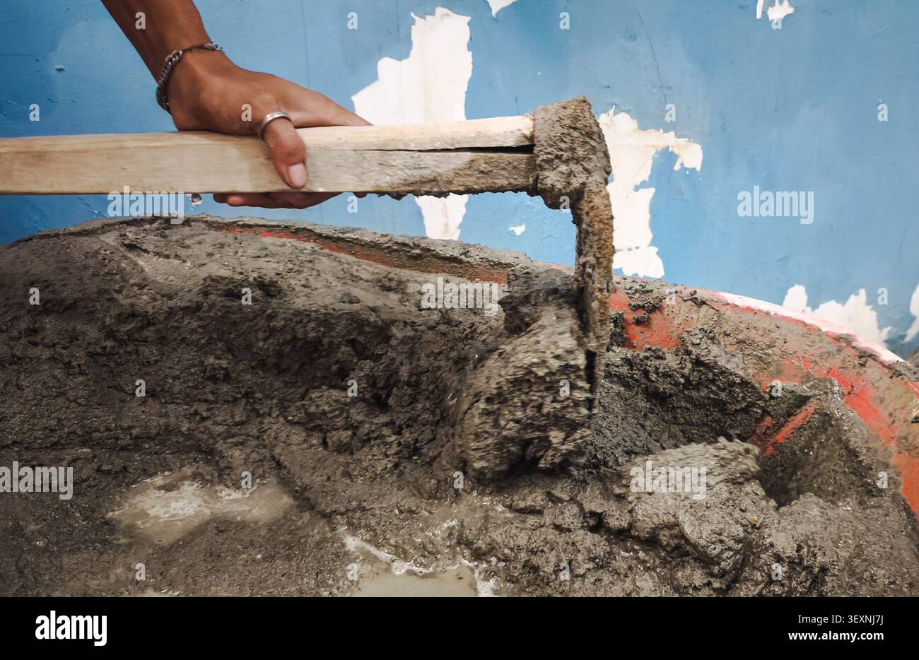 Travailleur de la construction mélangeant du ciment humide avec de la houe dans un bac de mortier pour les travaux de construction de maçonnerie et de béton gros plan Banque D'Images