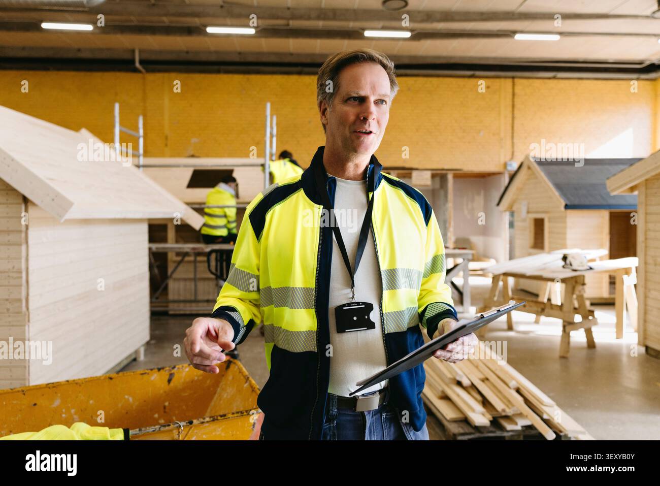 Professionnel de l'éducation masculin tenant bloc-notes donnant des instructions dans la construction et le génie civil classe à haut SC Banque D'Images
