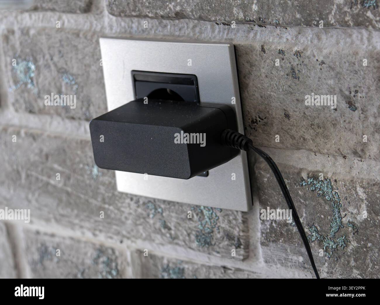 Chargeur branché à la prise murale dans l'intérieur moderne de la pièce Banque D'Images