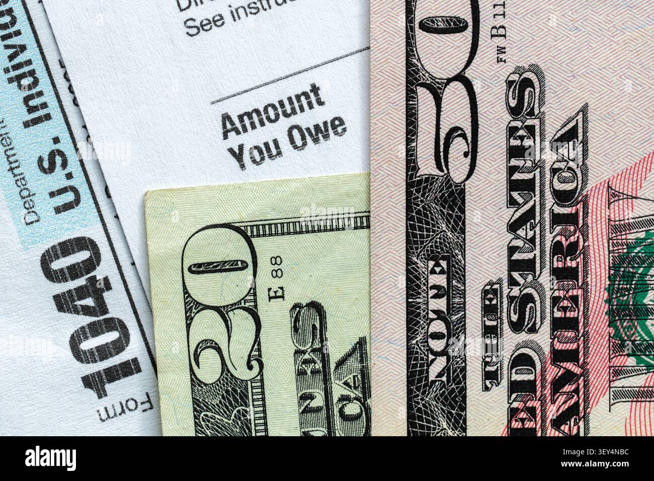 Billets en dollars AMÉRICAINS placés sur un formulaire 1040 Déclaration de revenus des particuliers indiquant « montant que vous devez », illustrant la dette fiscale, l’obligation de paiement. Banque D'Images