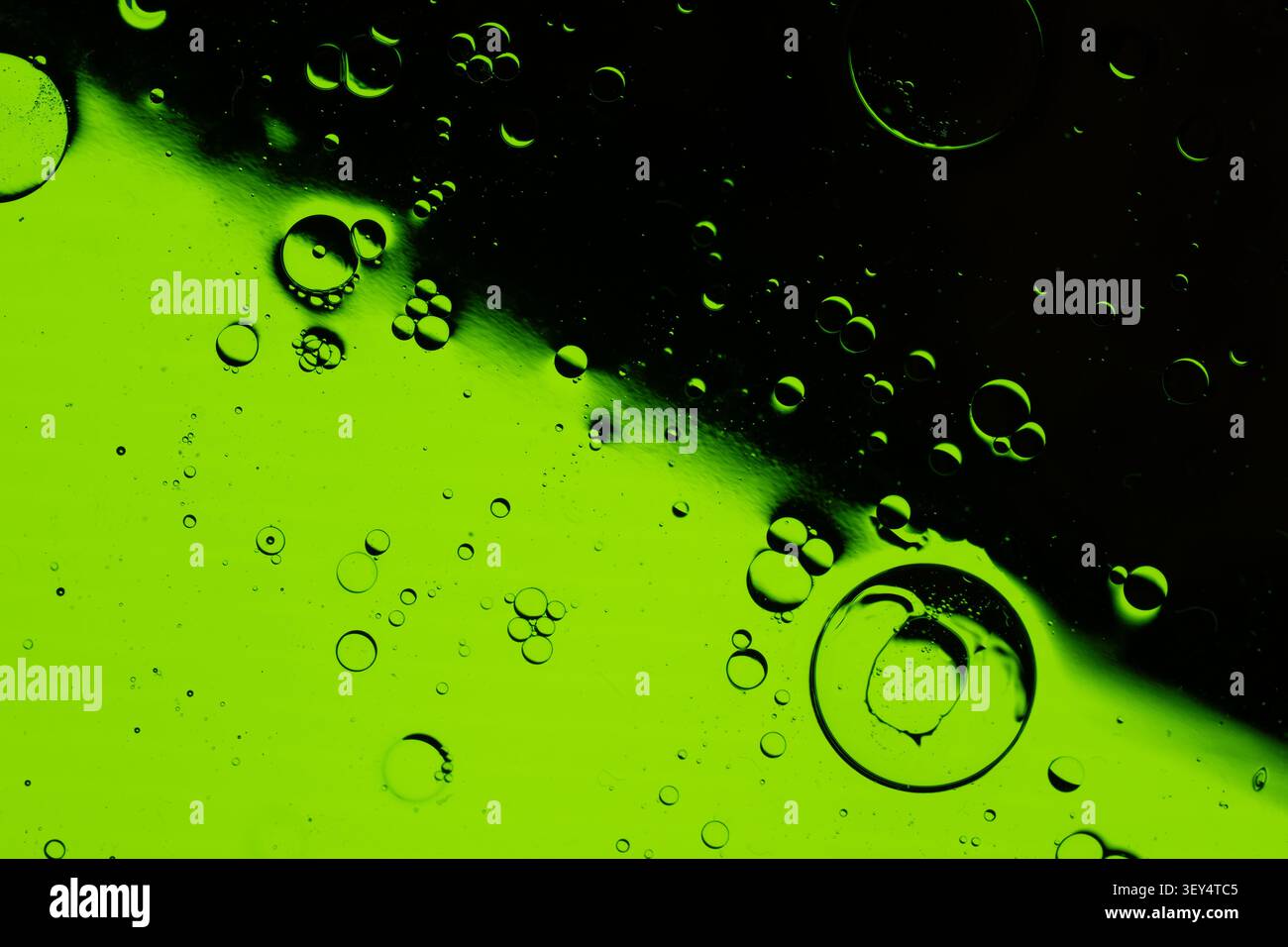 Les bulles d'air flottent à l'intérieur du fluide translucide vert vif, créant une texture abstraite spectaculaire avec une partie supérieure sombre, un éclairage à contraste élevé et des détails macro Banque D'Images