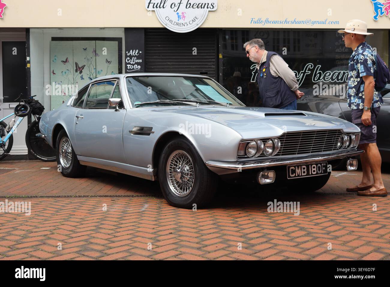 Un homme lit la fiche d'information sur l'historique du véhicule d'une Aston Martin DBS classique de 1968 exposée lors d'un salon de voitures de collection. Banque D'Images