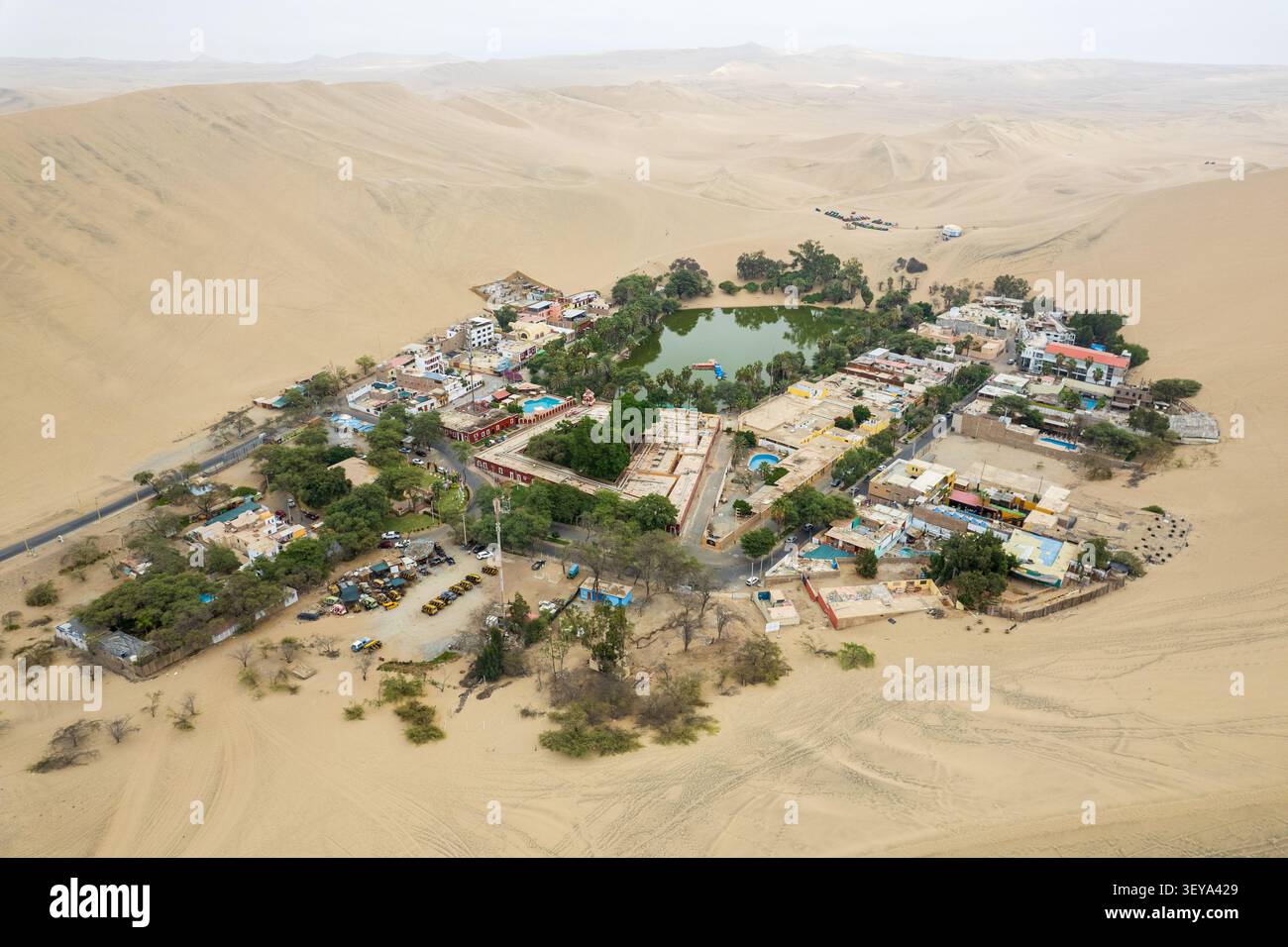 Vue aérienne de l'oasis de Huacachina entourée de vastes dunes de sable, de palmiers et de bâtiments à Huacachina, ICA, Pérou. Banque D'Images