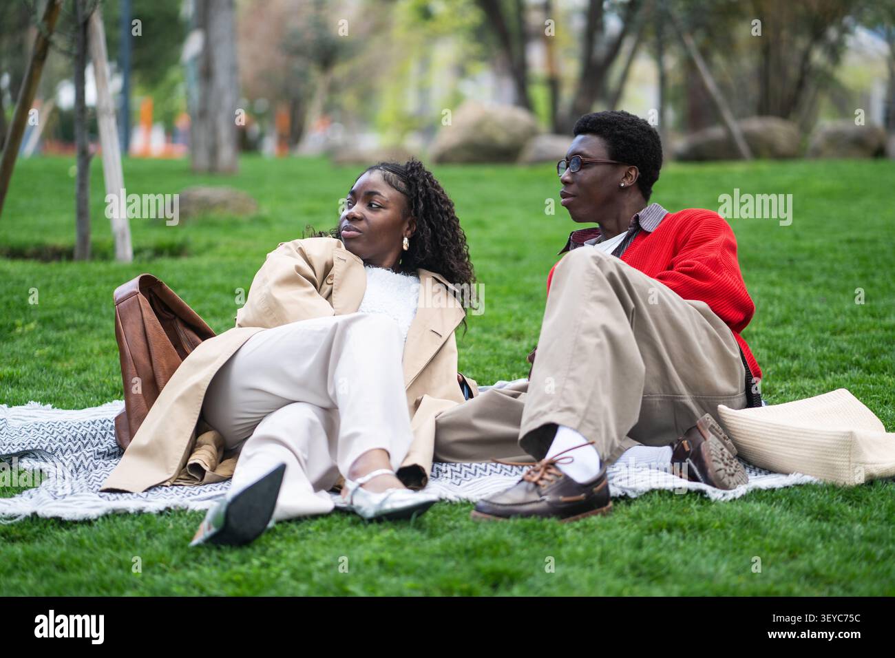 Détendu couple afro-américain insouciant homme et femme amis se reposant à l'extérieur sur l'herbe dans le parc. Banque D'Images