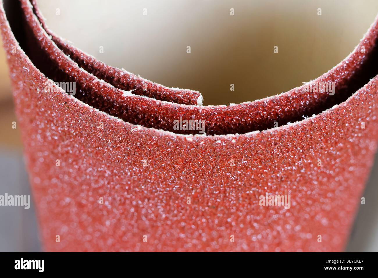 Un gros plan de papier abrasif rouge roulé avec texture rugueuse et grain fin pour poncer et polir les surfaces Banque D'Images