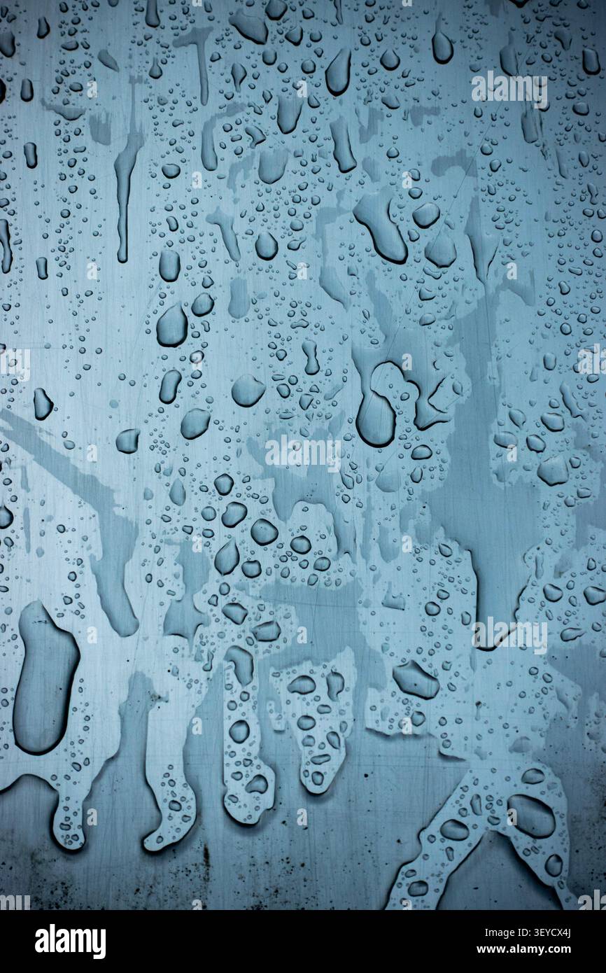 Gros plan abstrait bleu de gouttelettes d'eau sur une surface texturée peinte avec des tons froids Banque D'Images