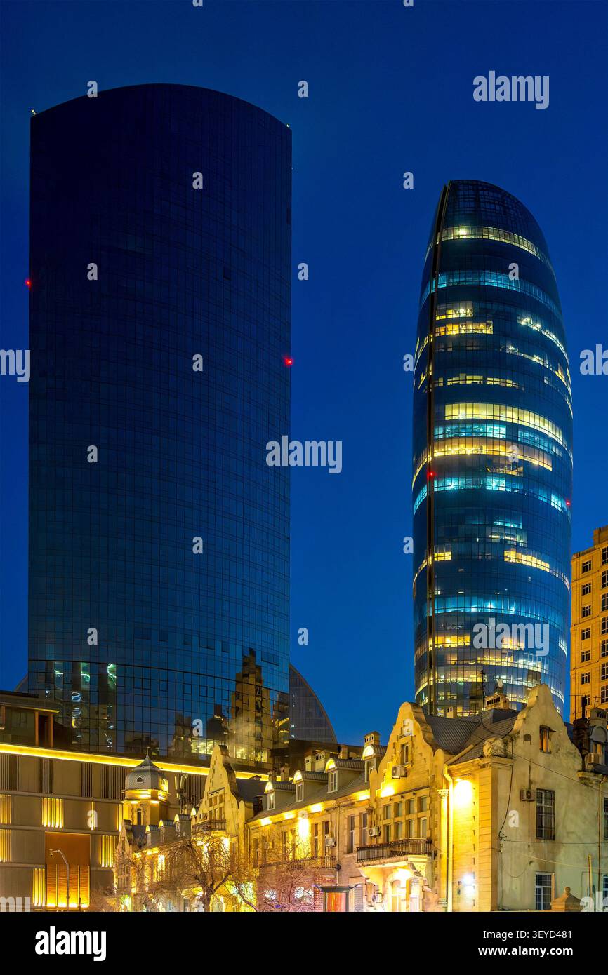 Les gratte-ciels en verre de Port Baku Tower 2 et Tower 1 s'élèvent au-dessus des bâtiments historiques de l'époque du boom pétrolier la nuit. Bakou, Azerbaïdjan. Banque D'Images