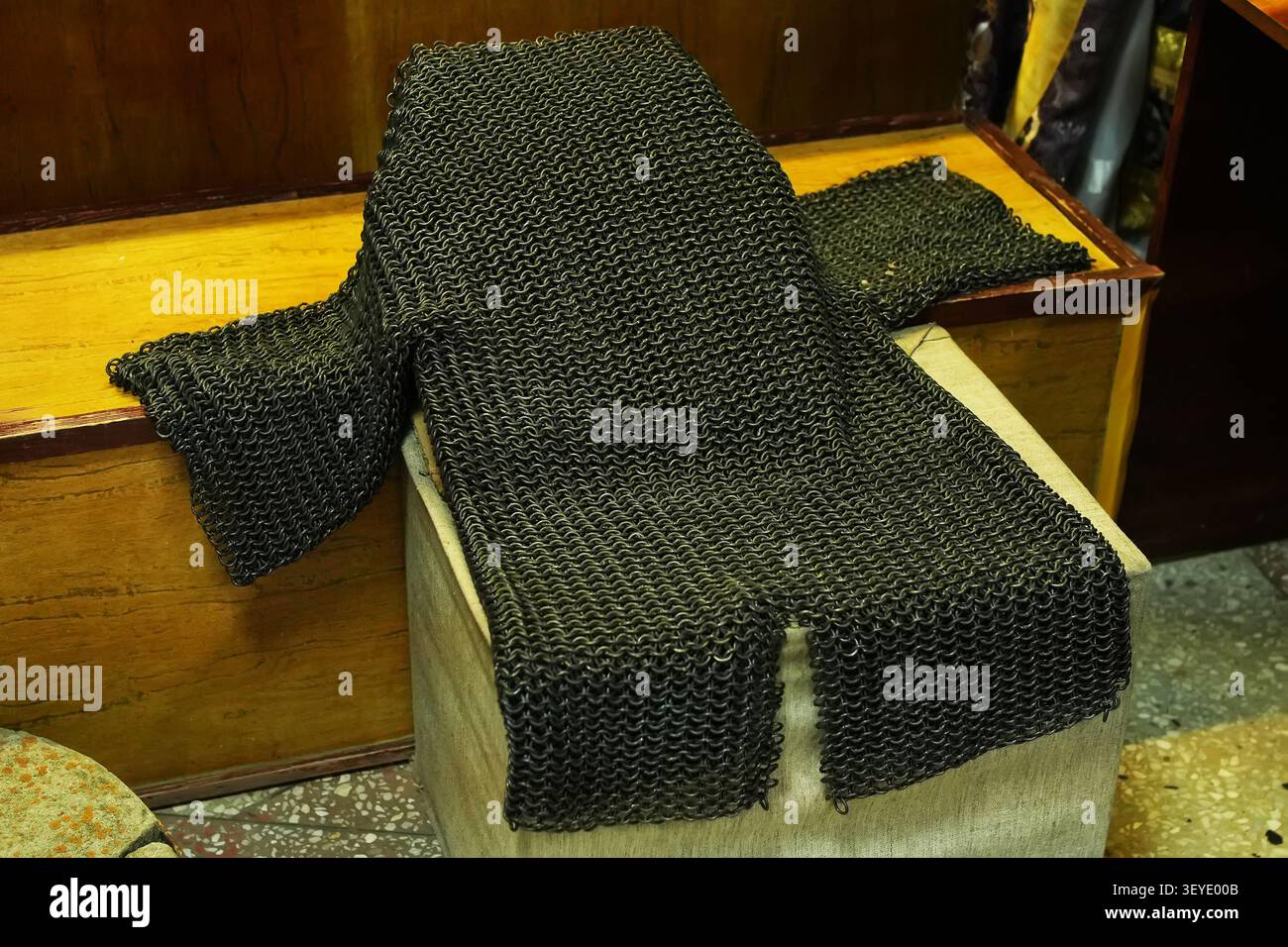 Armure en cotte de mailles médiévale posée sur un vieux coffre en bois dans un musée historique ou un atelier. Équipement de protection en fer. Banque D'Images