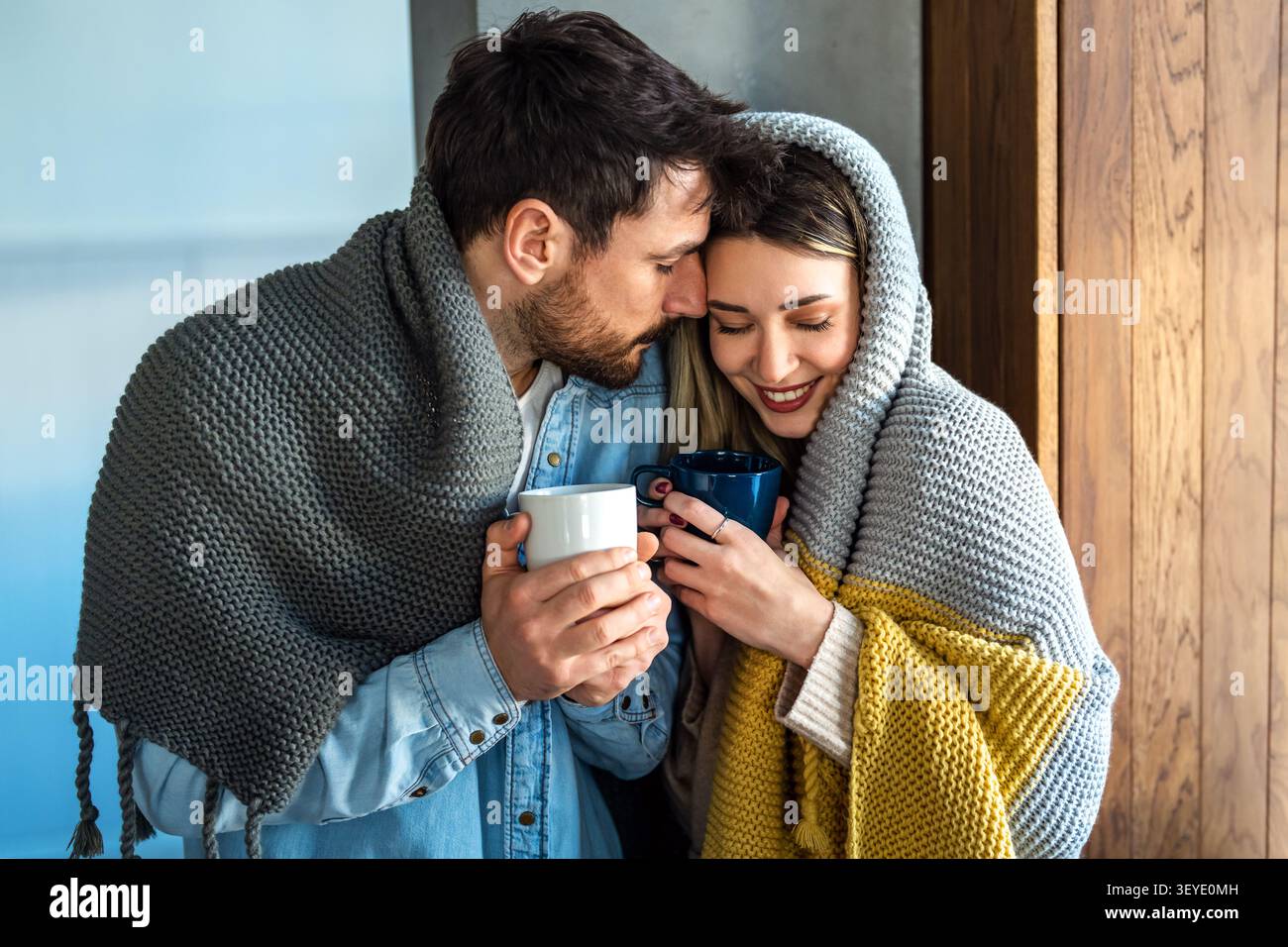 Un couple aimant partage un matin d'hiver tranquille enveloppé dans des couvertures chaudes, trouvant une intimité émotionnelle Banque D'Images