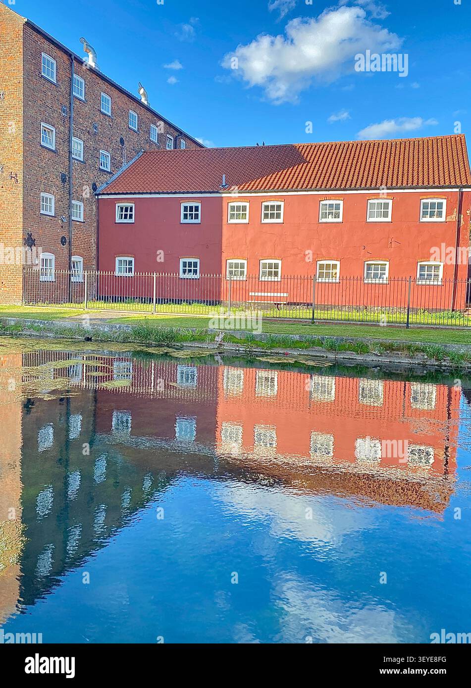 Bâtiment rose au bord du canal réfléchi dans l'eau calme, réflexion architecturale avec composition symétrique. Banque D'Images