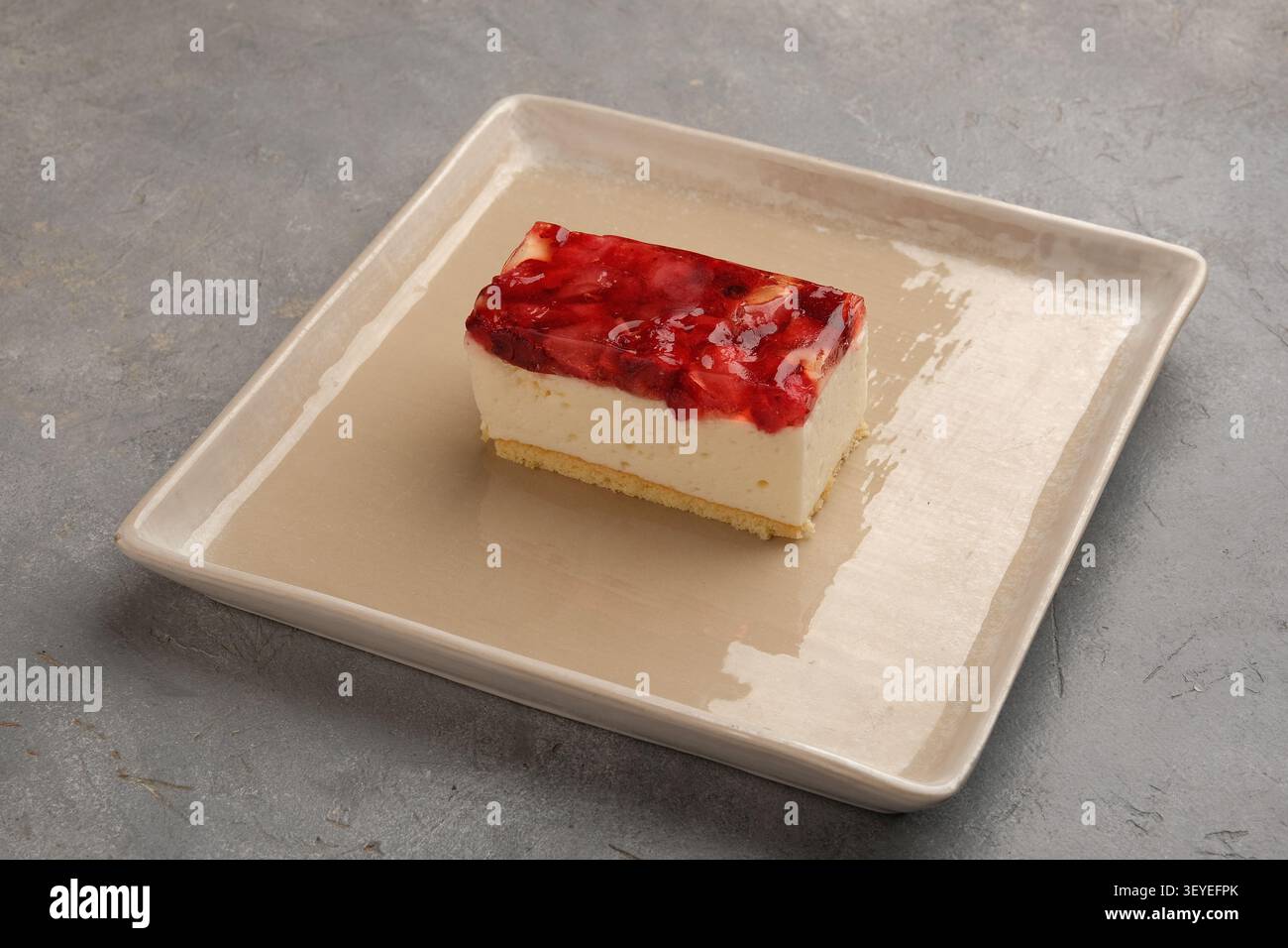 Tranche de cheesecake à la fraise sur plaque de céramique beige contre surface de pierre grise texturée Banque D'Images