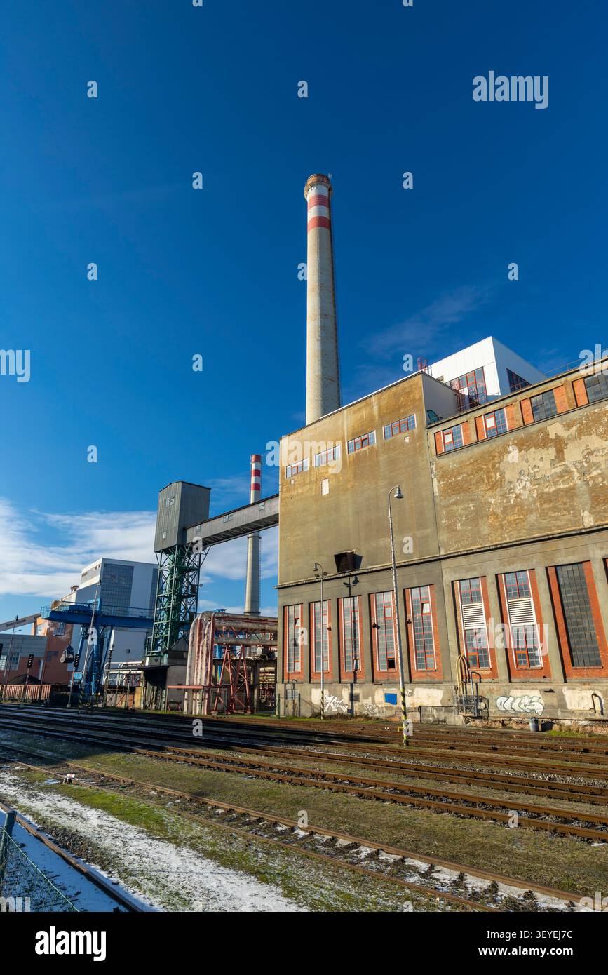Paysage industriel avec de vieux bâtiments d'usine, des cheminées imposantes et des lignes de chemin de fer parallèles Banque D'Images