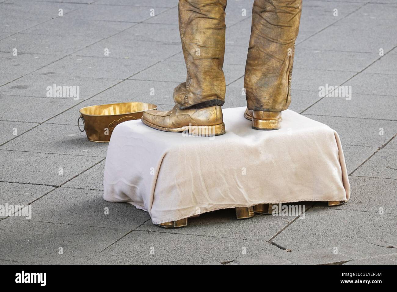 Statue vivante artiste de rue peint en or se produit sur la rue de la ville avec seau doré Banque D'Images