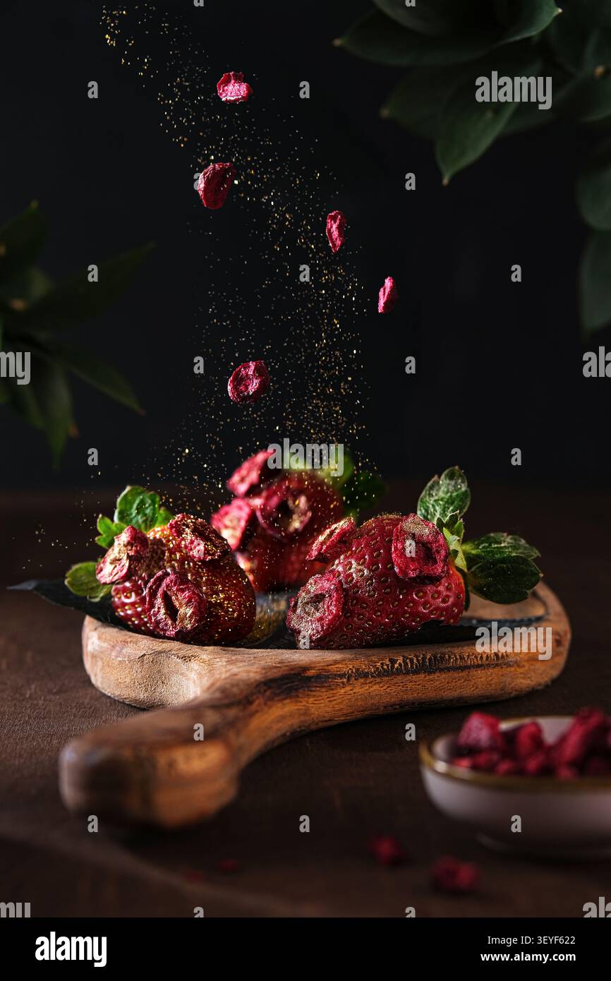 Fraises fraîches à la menthe sur planche de bois rustique sur fond dramatique sombre Banque D'Images