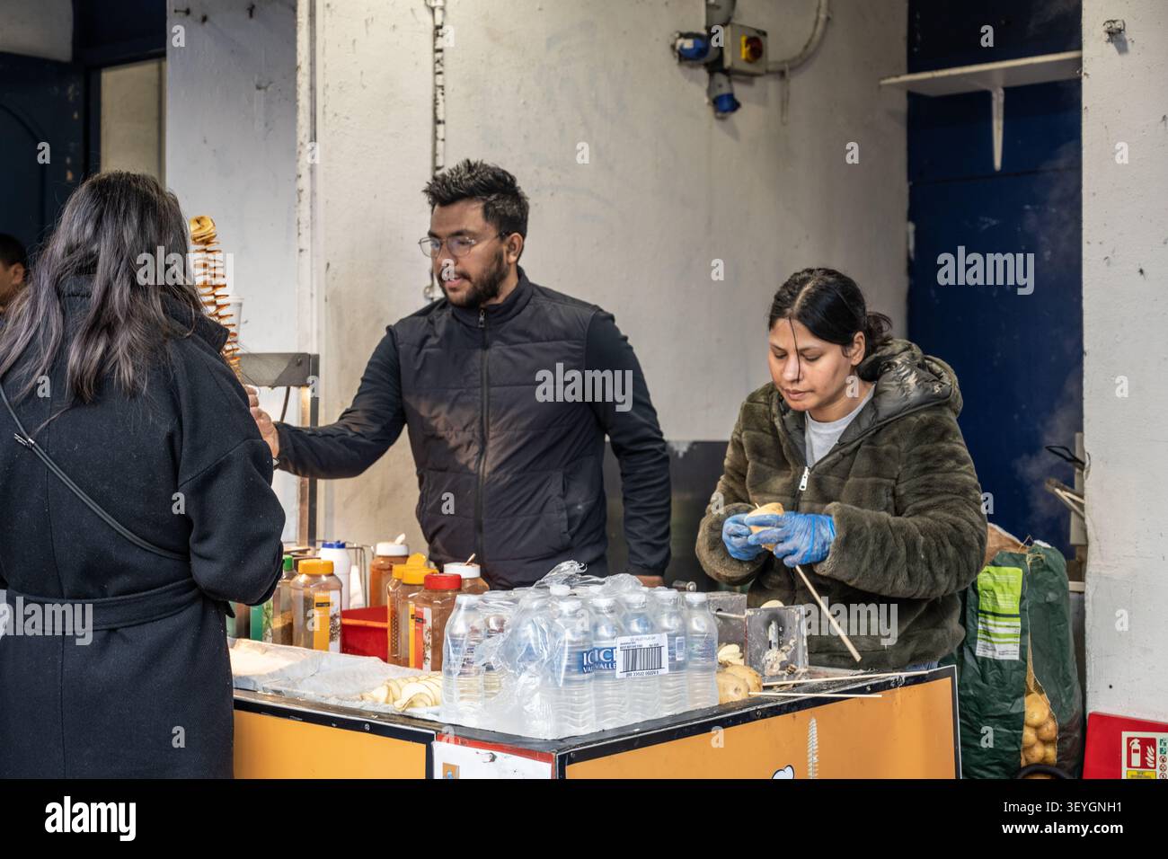 Vendeurs de nourriture de rue préparant des chips de pommes de terre en spirale sur un stand de marché en plein air sur Portobello Road à Notting Hill, Londres, Royaume-Uni. Banque D'Images