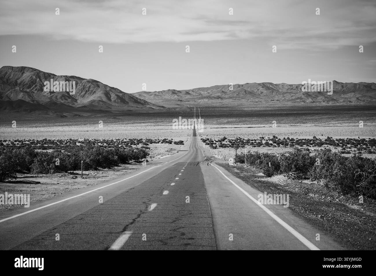 Une longue autoroute droite traversant le désert près de la frontière du Nevada en Californie. Image en noir et blanc. Banque D'Images