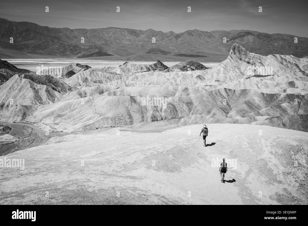 Deux randonneurs dans le désert à Zabriskie point le long de la route 191. Parc national de la Vallée de la mort, Californie, États-Unis. Image en noir et blanc. Banque D'Images