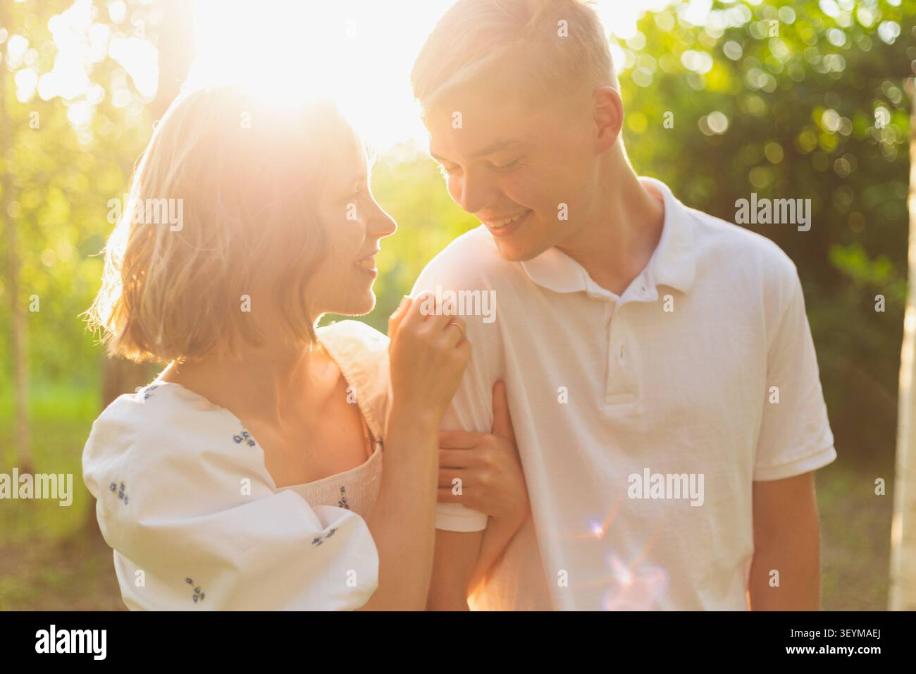 Un couple partage un moment tendre dans une forêt ensoleillée, soulignant leur amour et leur connexion Banque D'Images