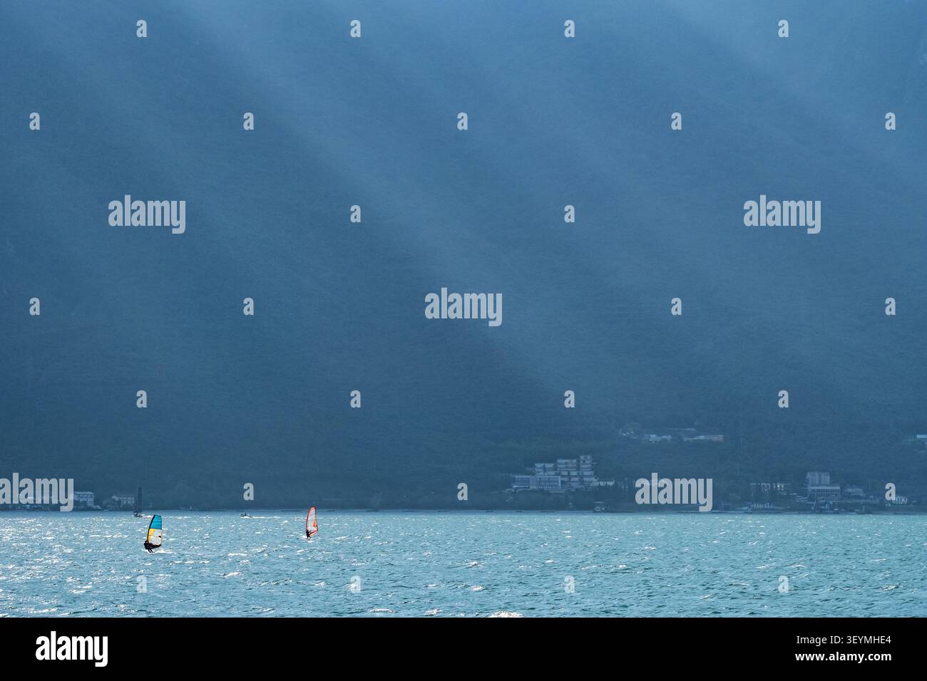 Windsurfers sous les rayons du soleil sur le lac de Garde, Italie Banque D'Images