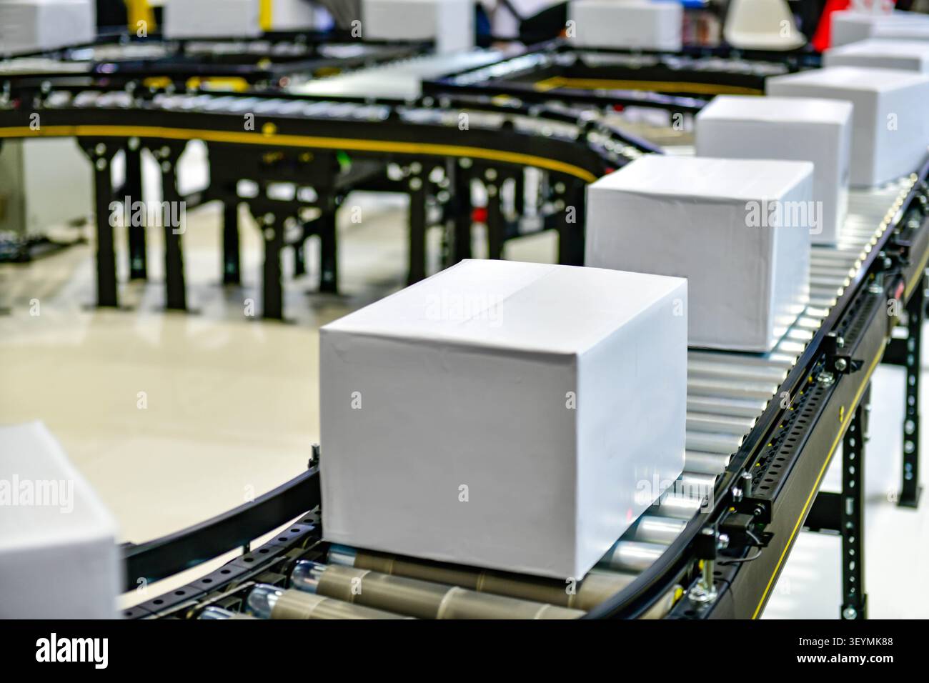 Système de convoyeur automatisé transportant des boîtes en carton blanc vierges dans un centre logistique moderne de distribution Banque D'Images