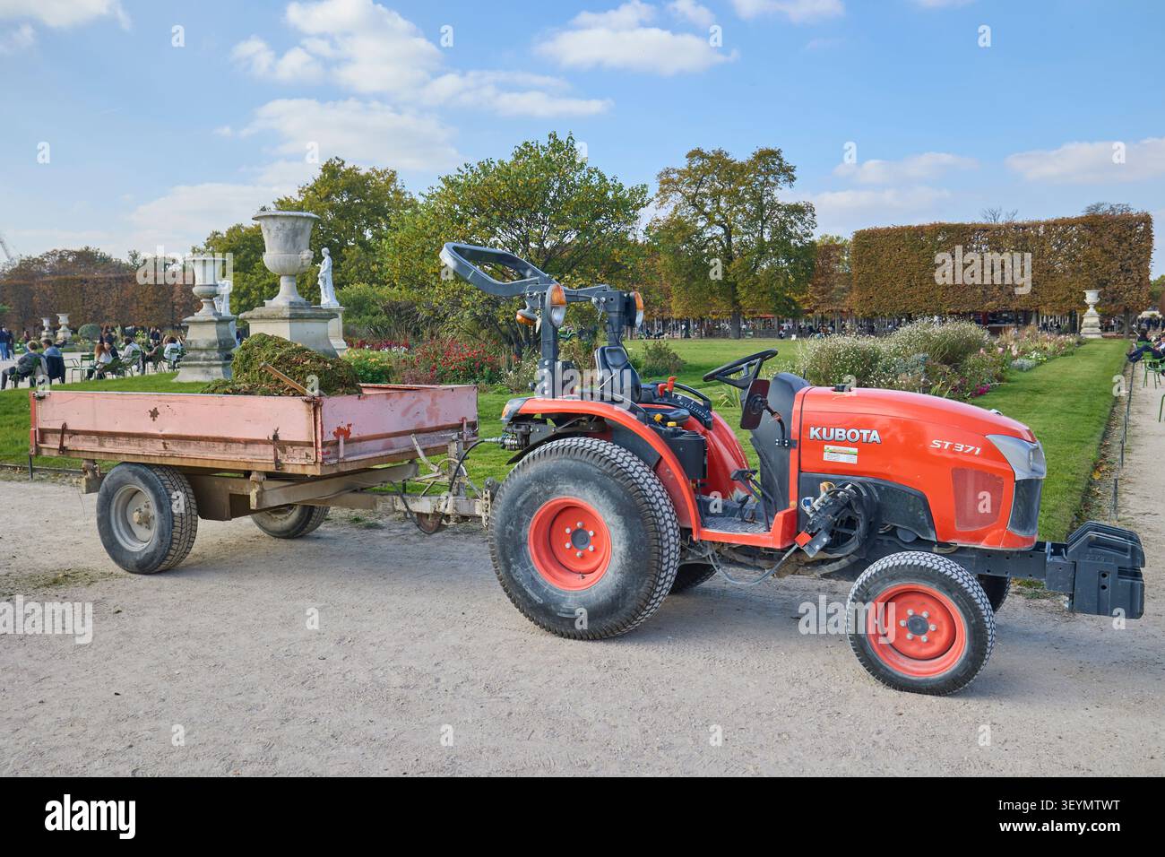 Petit tracteur avec remorque dans les travaux d'entretien du jardin du parc parisien. Paris, France - 14 octobre 2025. Banque D'Images