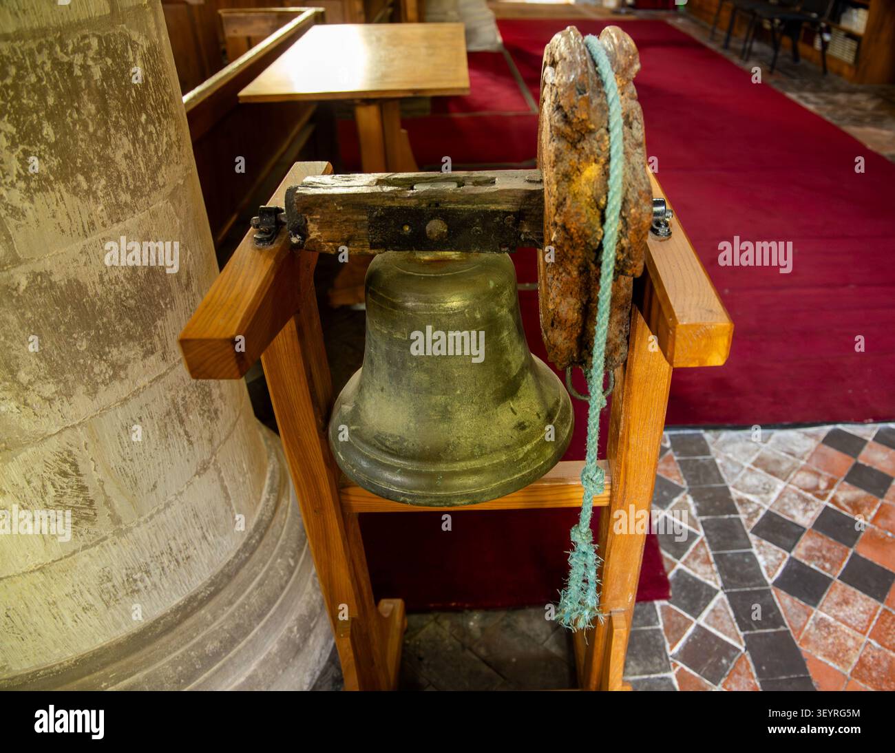 Une cloche d'église vintage en bronze montée sur un support en bois à l'intérieur avec une corde attachée pour le sonnage manuel de l'église Saint-Pierre Over Wallop Banque D'Images