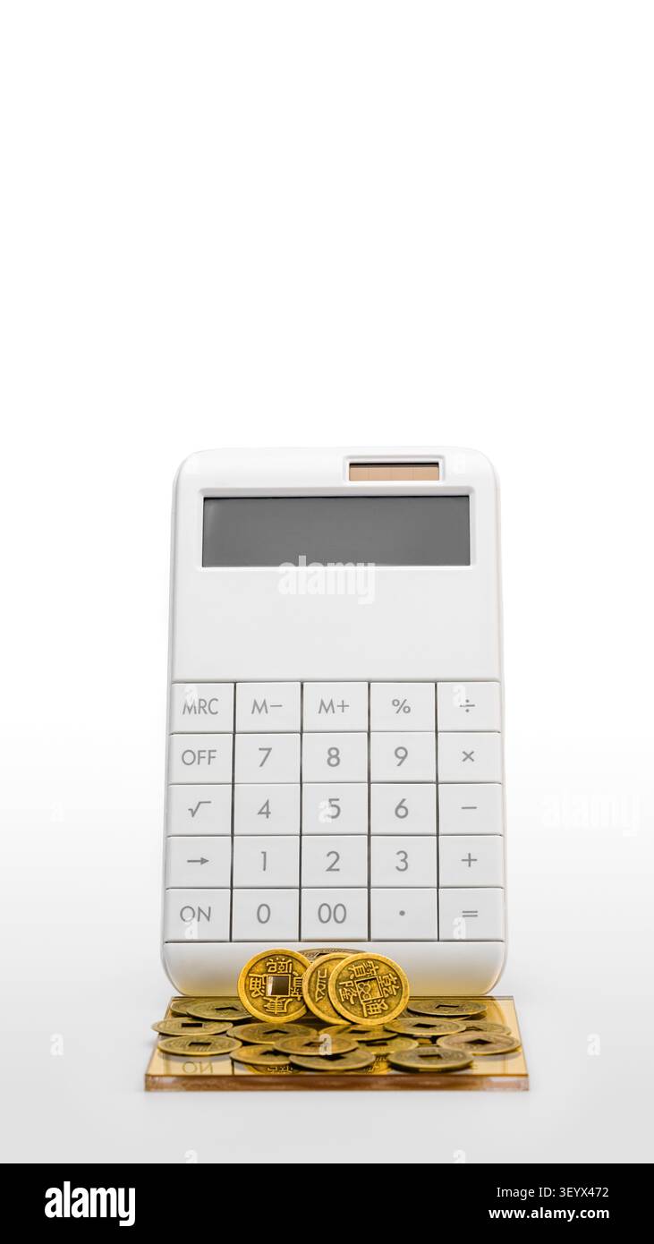 Calculateur blanc avec des pièces de fortune chinoises sur fond blanc. Planification financière et richesse. Banque D'Images