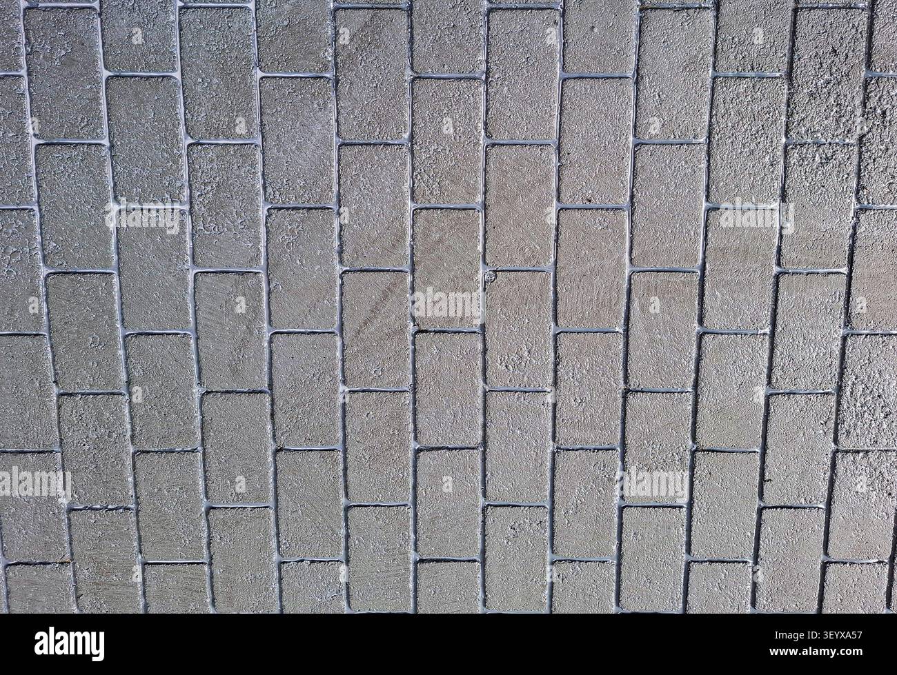 Les carreaux de pierre gris disposés dans un motif soigné fournissent un aspect propre et élégant pour divers espaces. Cette surface est idéale pour les patios, les allées, ou Banque D'Images