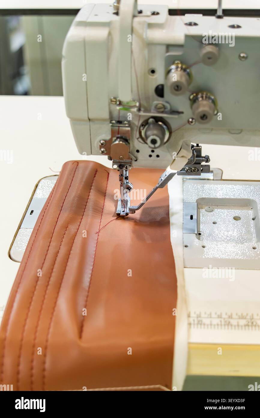 Pied presseur de machine à coudre moderne avec une aiguille coud du cuir marron. Banque D'Images