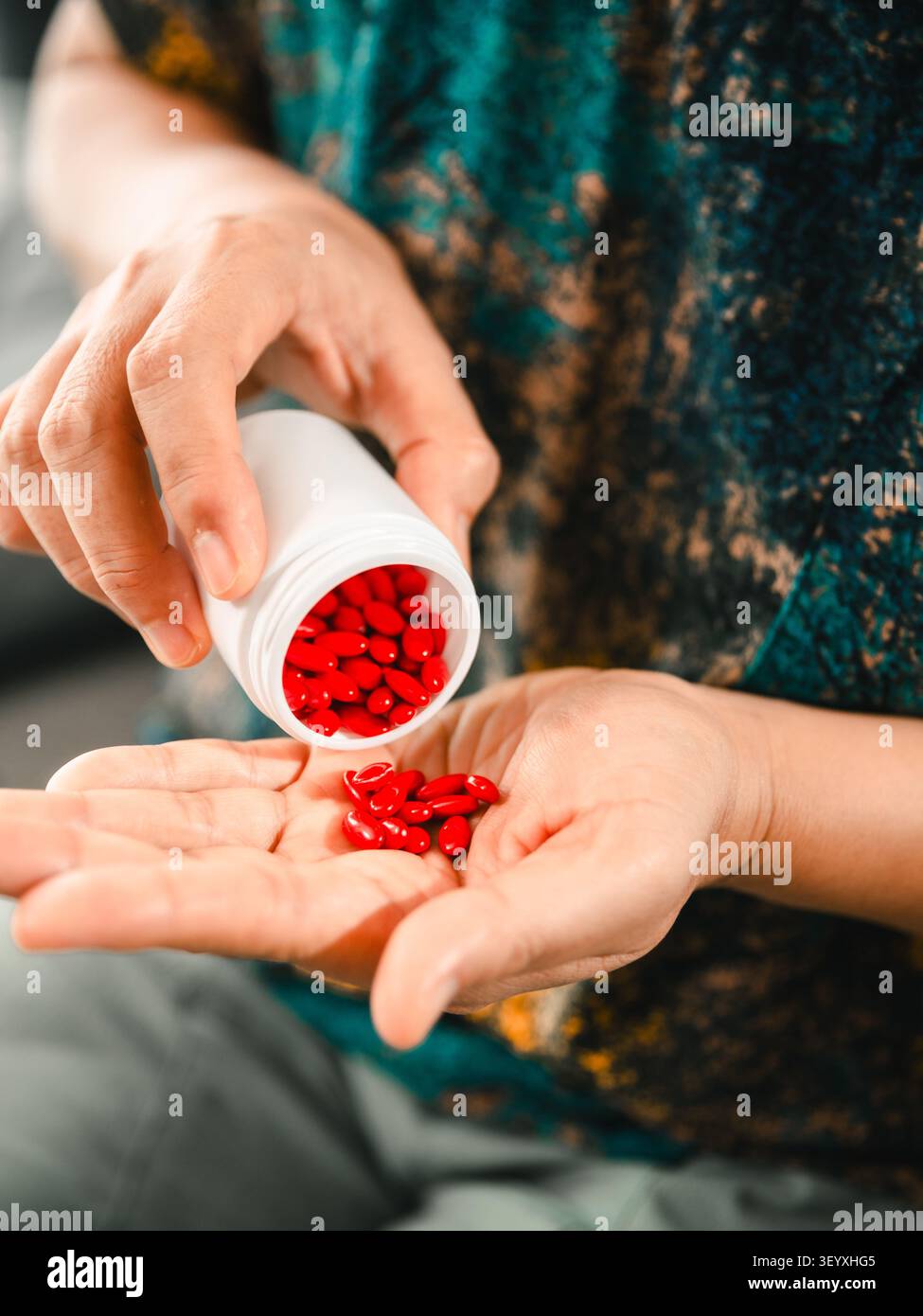 Gros plan de femme asiatique versant des pilules rouges de la bouteille de médecine dans la main à la maison, concept de soins de santé, médicaments, supplément, traitement, bien-être, Banque D'Images