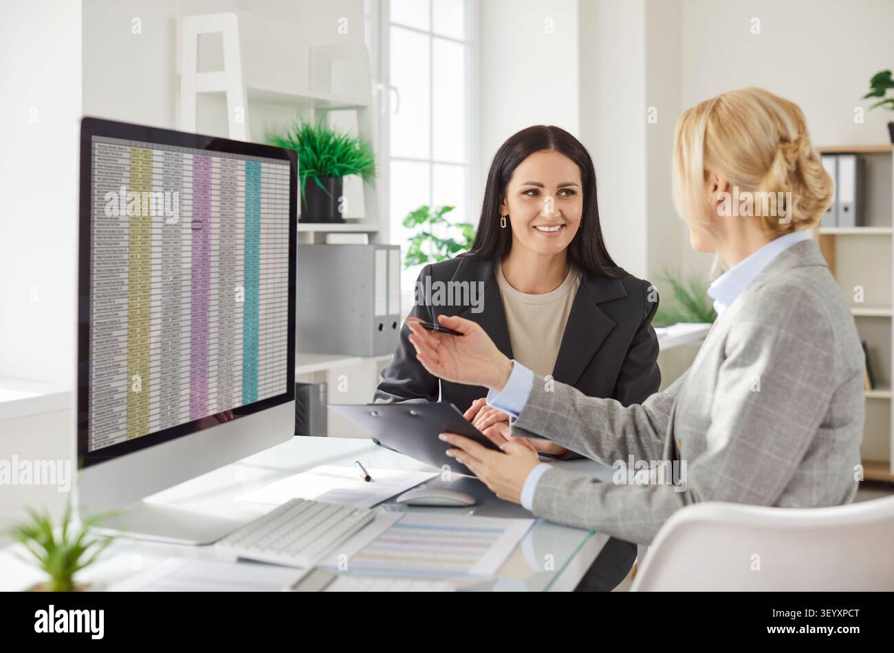 Deux femmes comptables financières discutant des données financières et analysant des feuilles de calcul au bureau. Banque D'Images