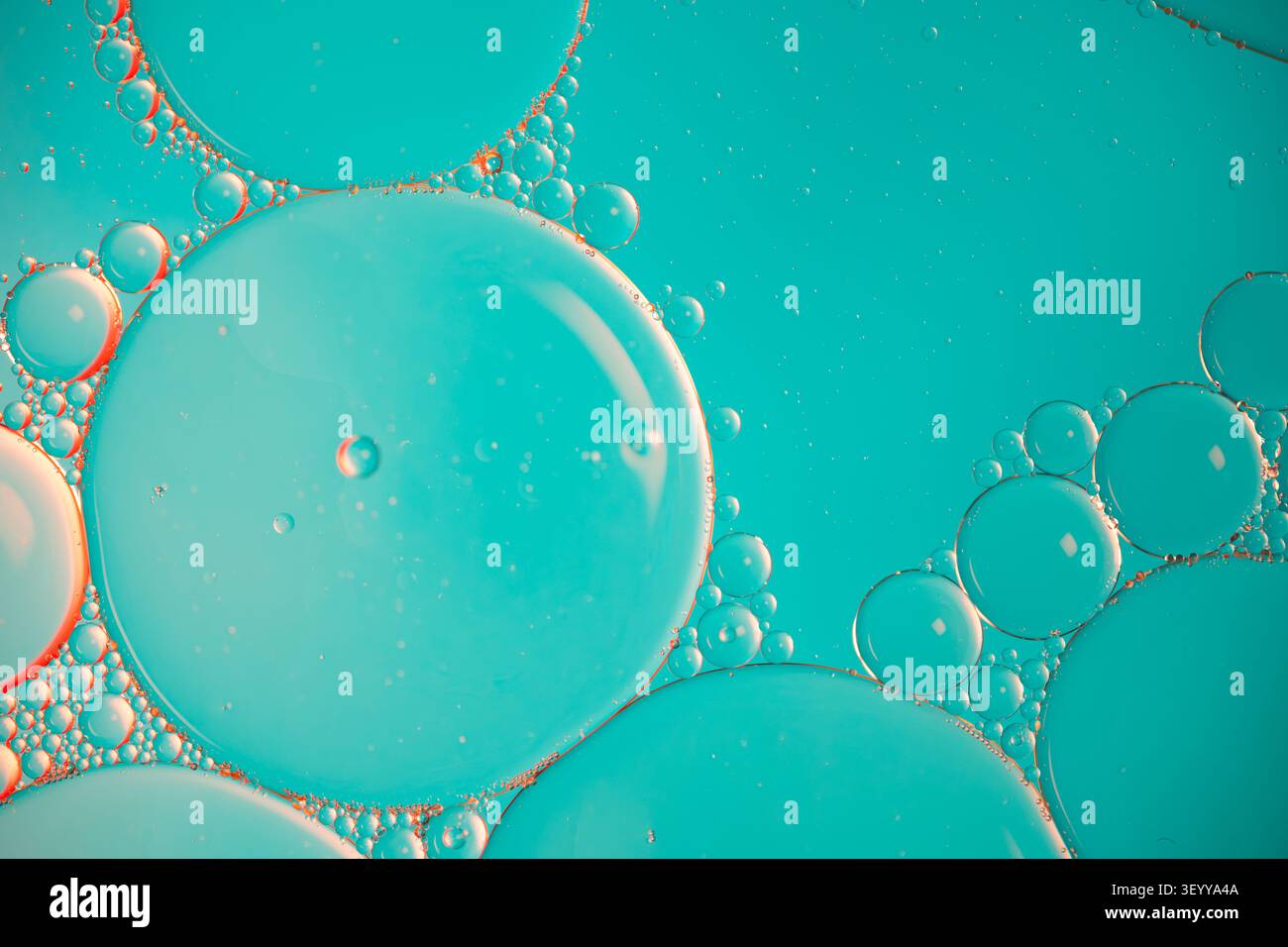 Photographie macro propre de gouttelettes d'huile flottantes sur un fond bleu clair et orange serein Banque D'Images
