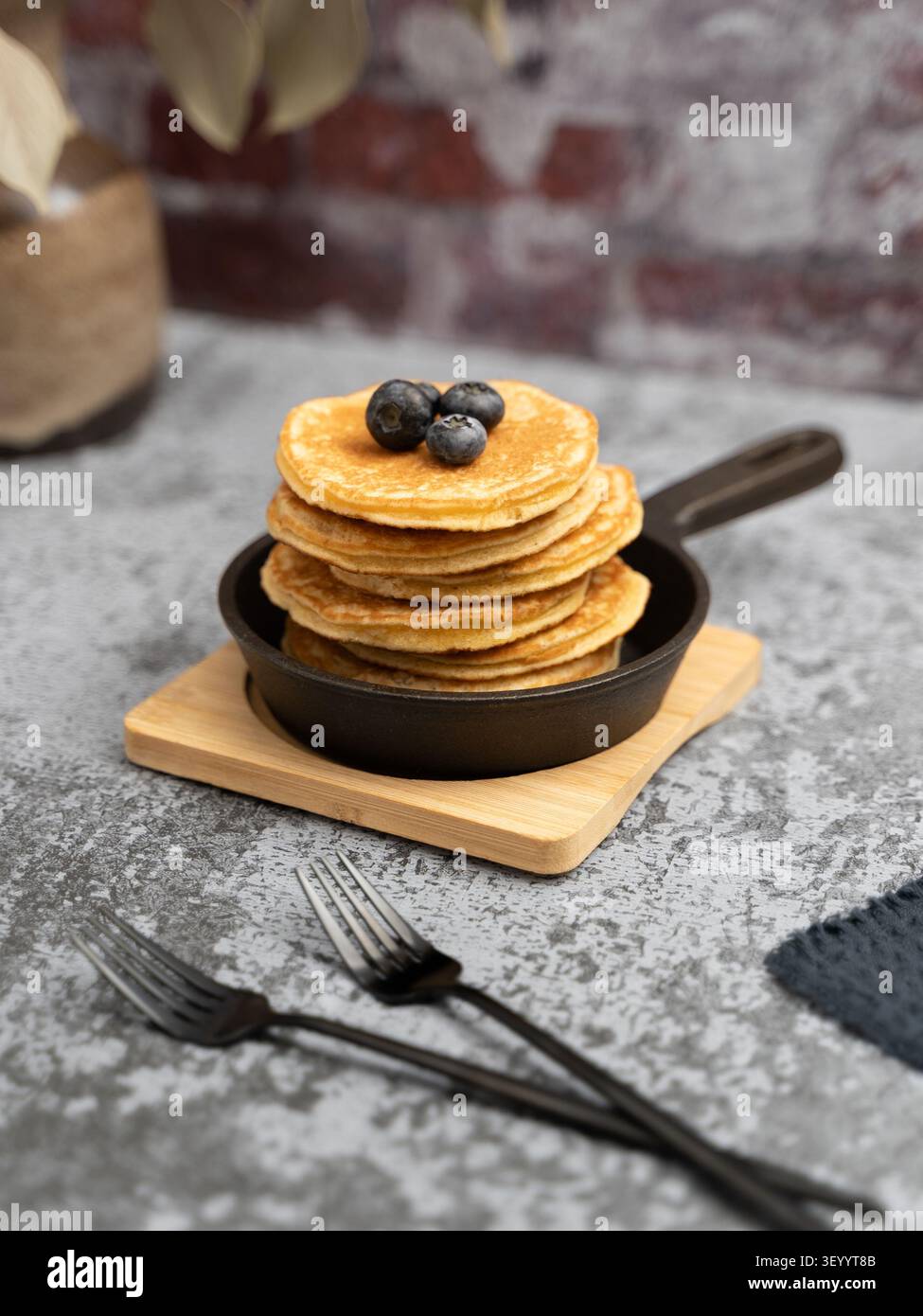 Petit-déjeuner rustique composé de crêpes moelleuses recouvertes de myrtilles et servies dans une poêle en fonte Banque D'Images